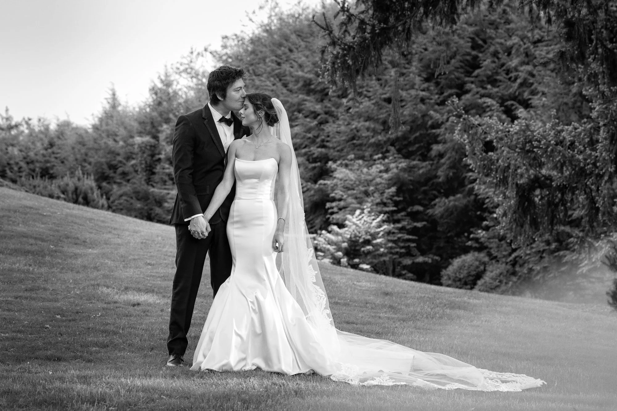 A forehead kiss from a groom to his bride on the grounds of Tappan Hill Mansion in New York,