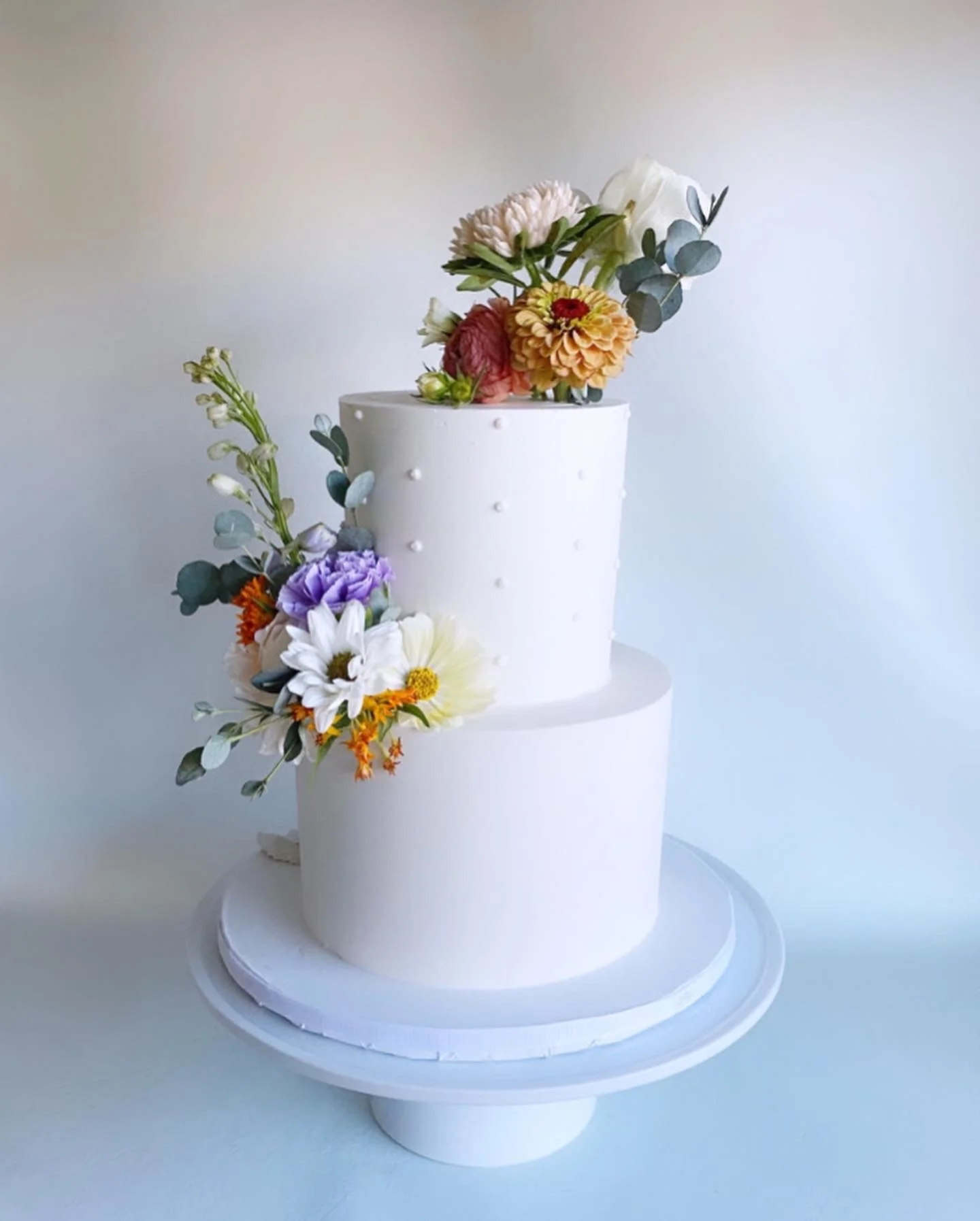 Evenly spaced pearls with smooth buttercream design and fresh flowers