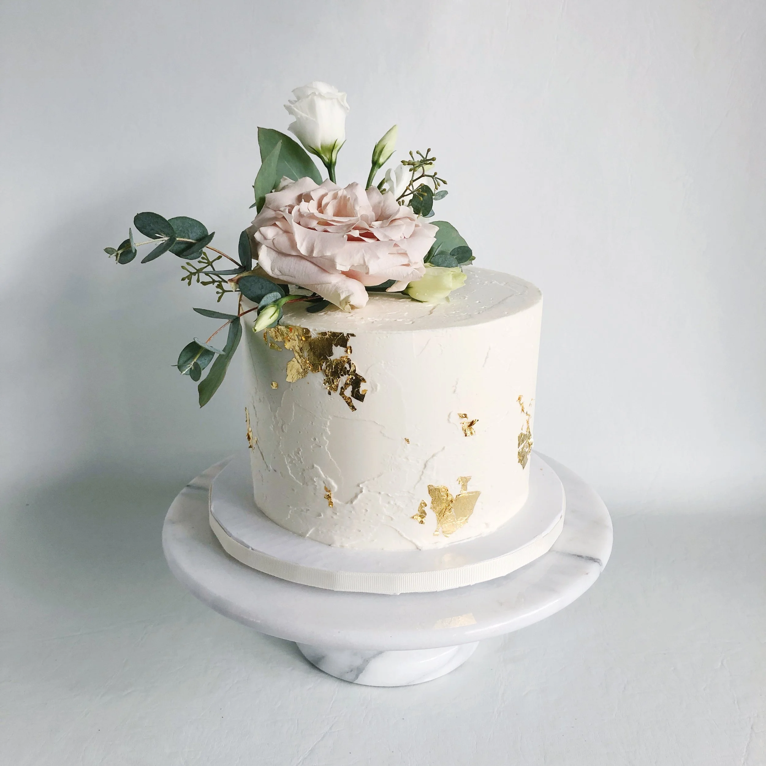 Soft textured buttercream with gold leaf flecks and fresh flowers