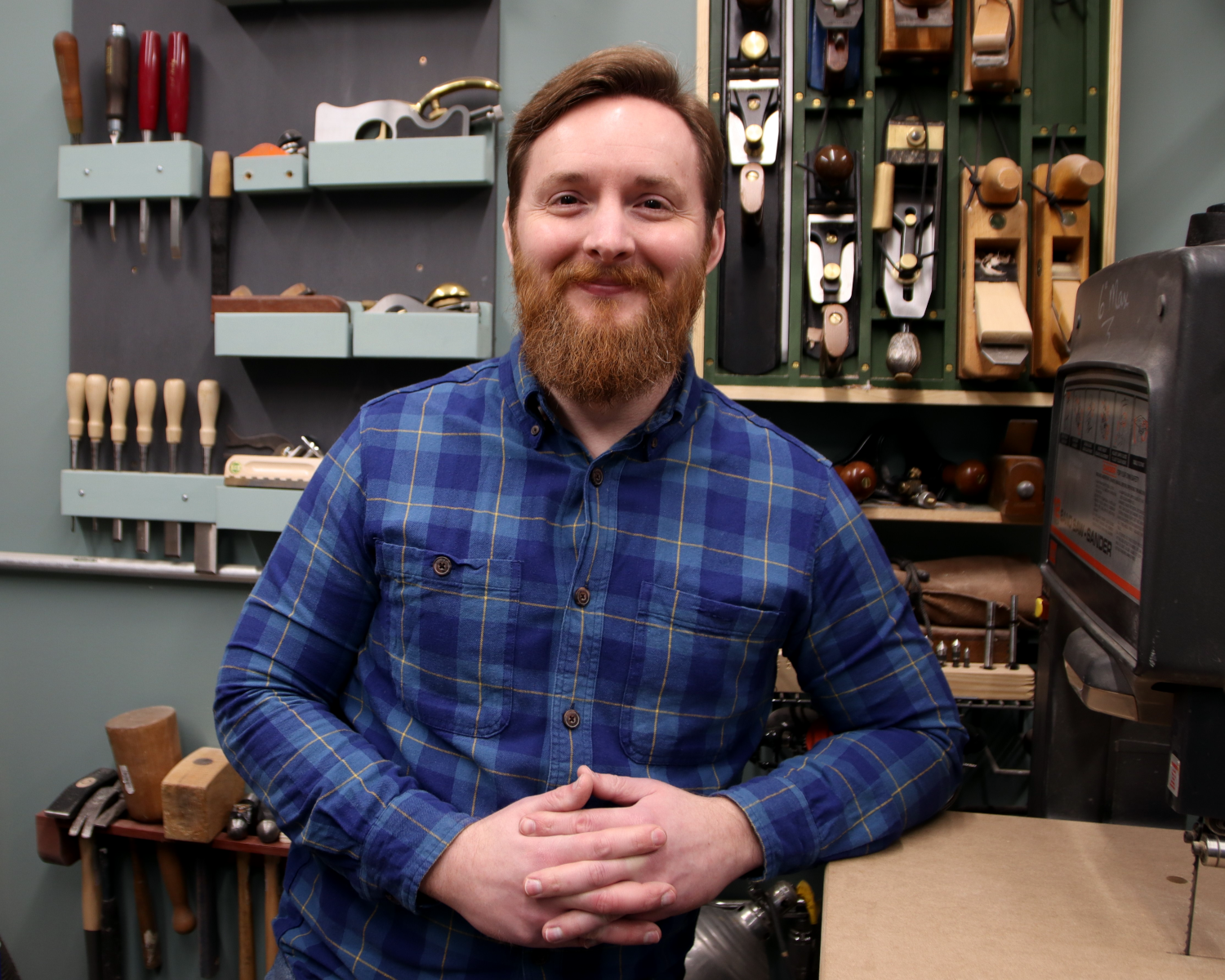 Eric leaning against a bandsaw in front of a wall of tools