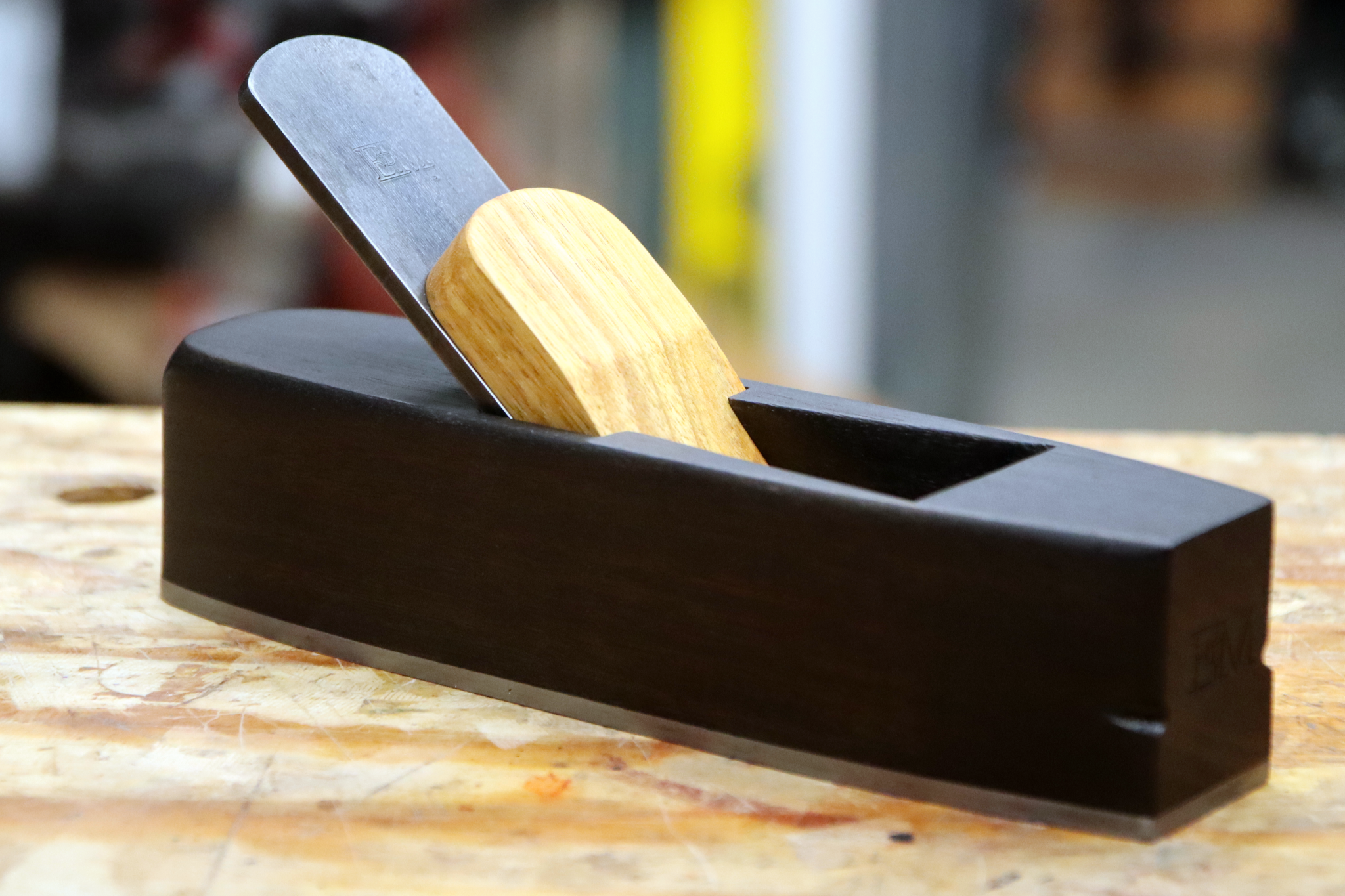 A miter plane made from ebonized canary wood sitting on a workbench.