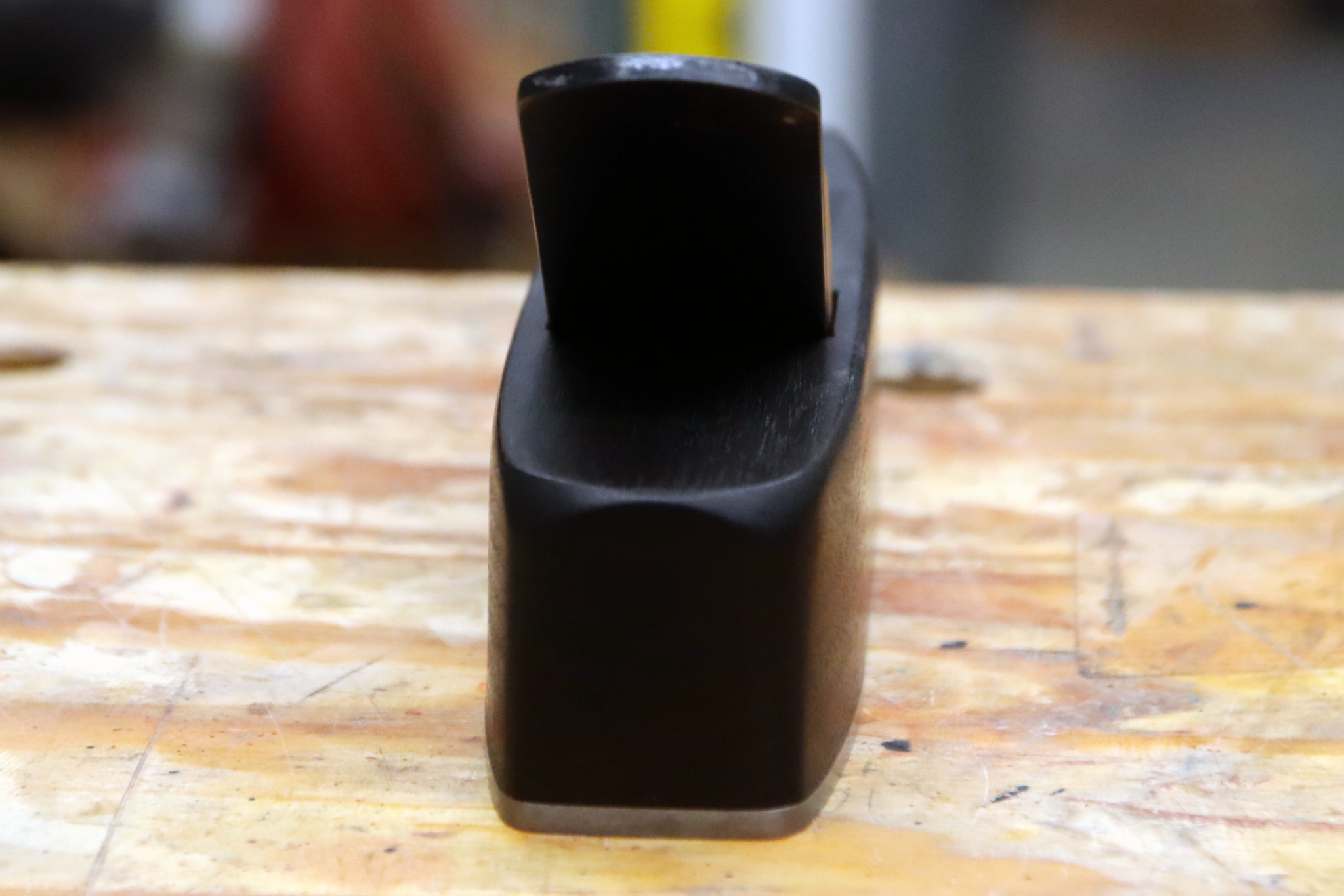 A miter plane made from ebonized canary wood sitting on a workbench.