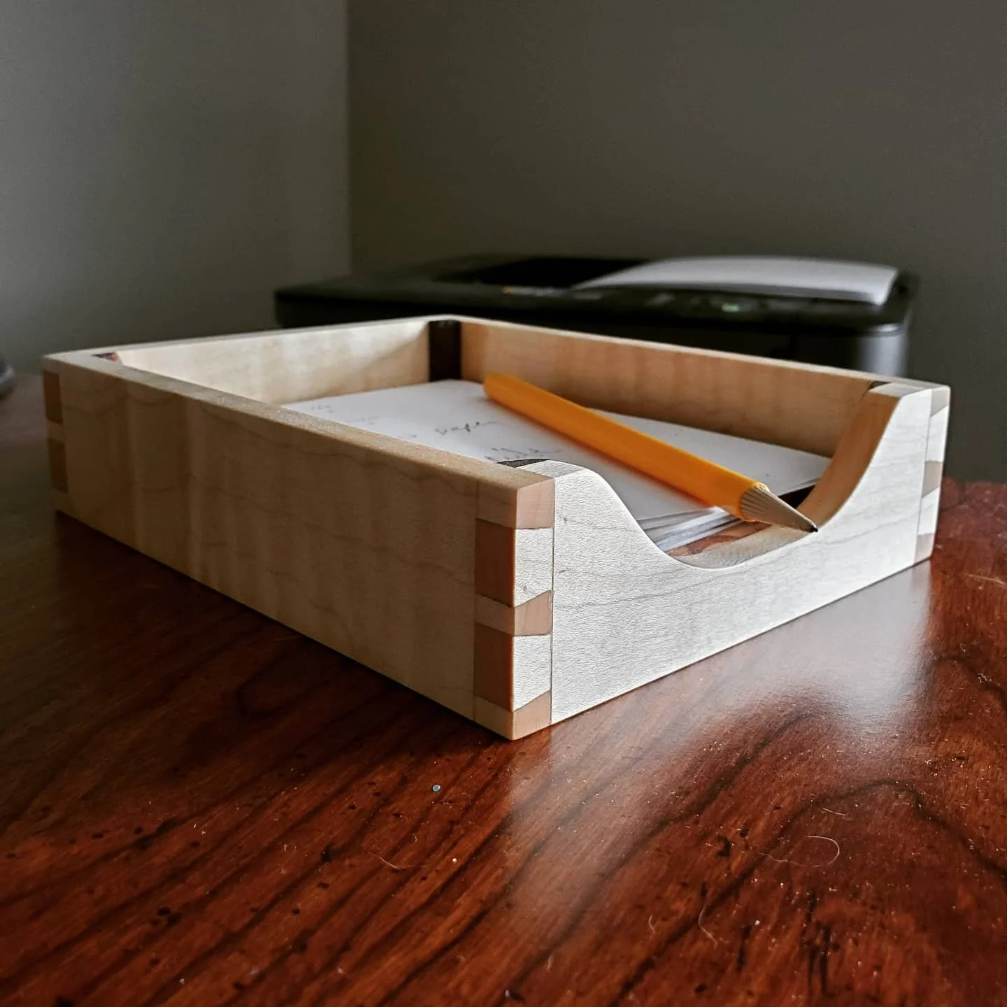 Paper tray filled with paper and a pencil sitting on a desk.