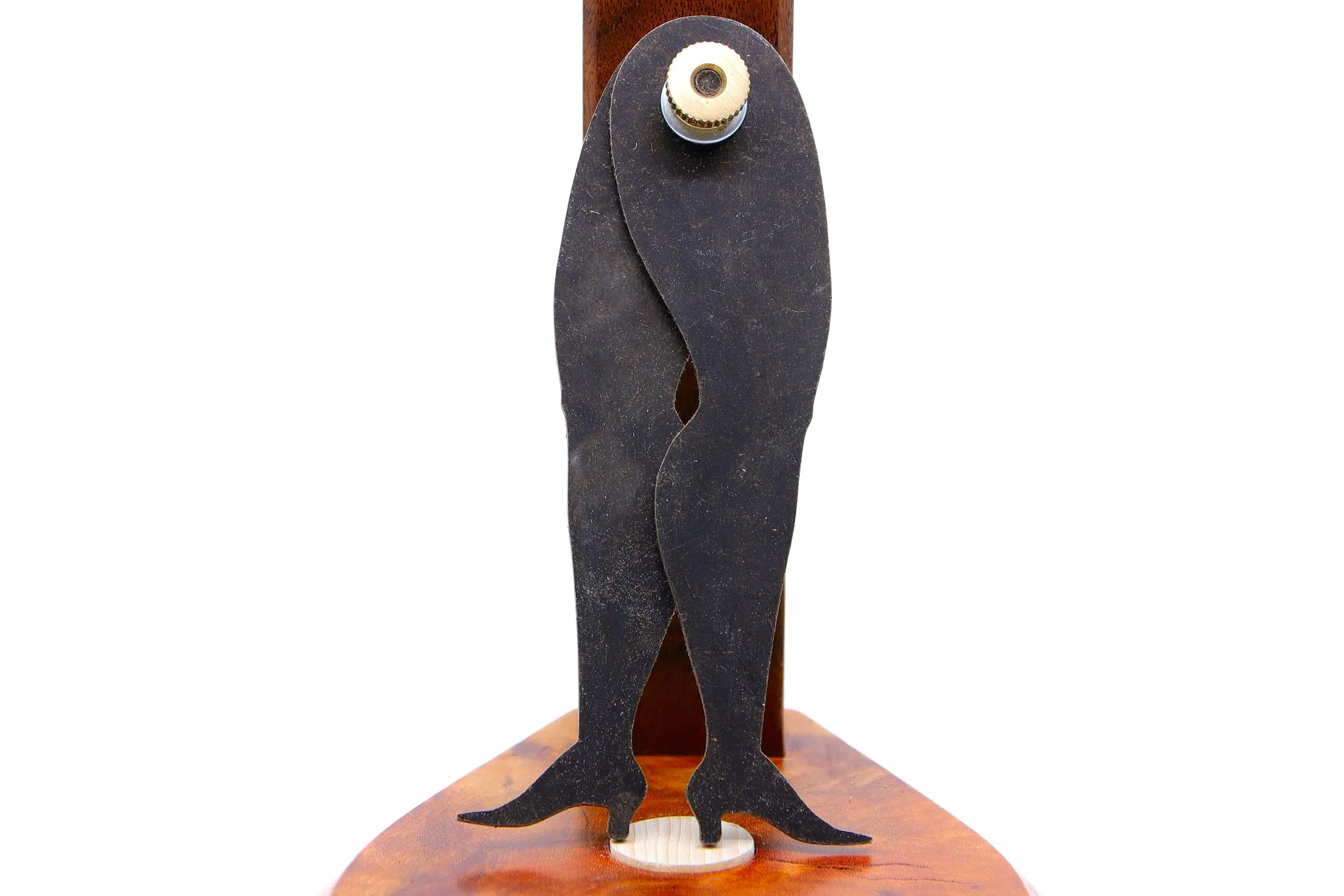 Legs with high-heeled boot shaped caliper propped up against a piece of burled walnut stand.