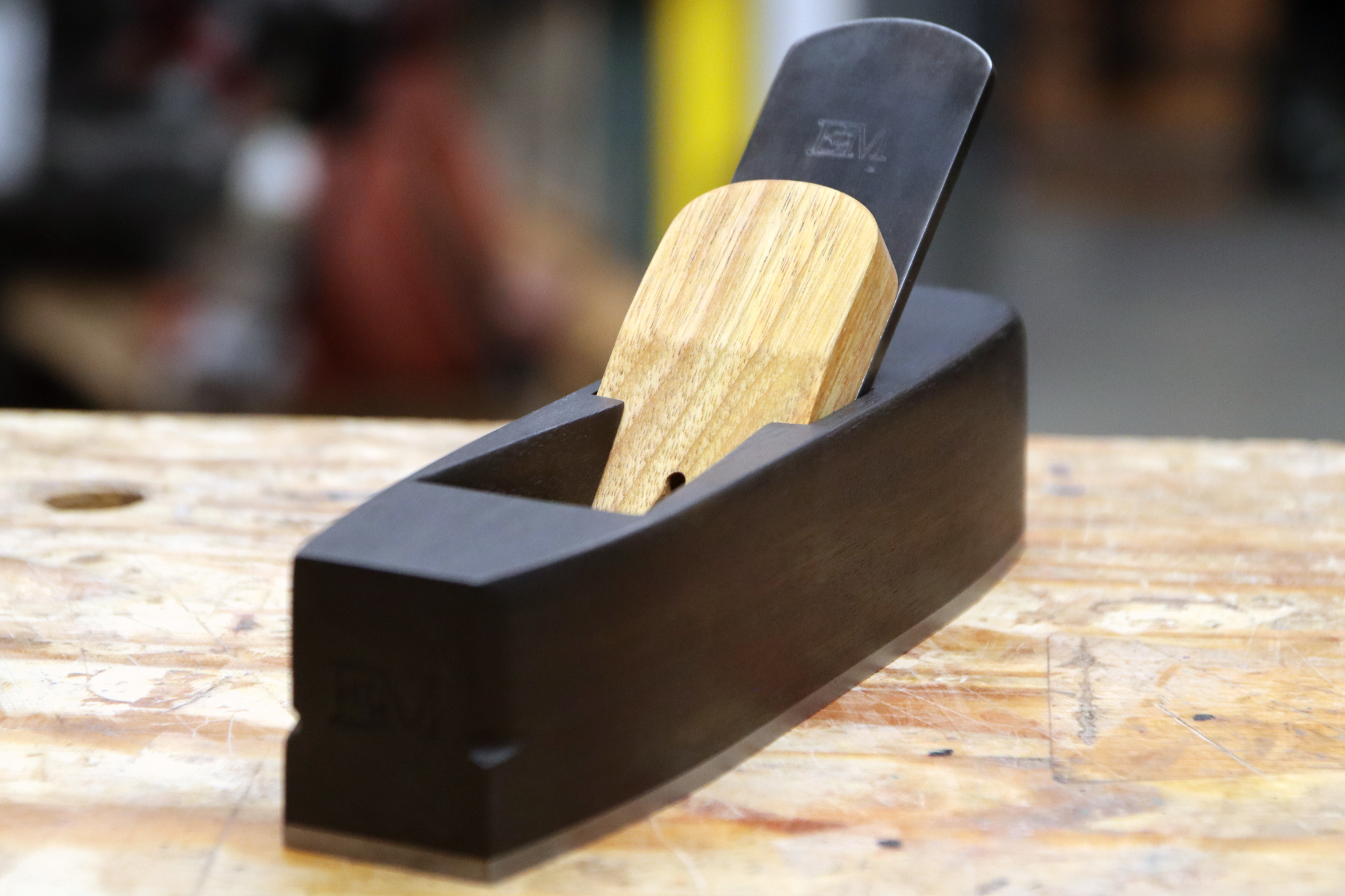 A miter plane made from ebonized canary wood sitting on a workbench.