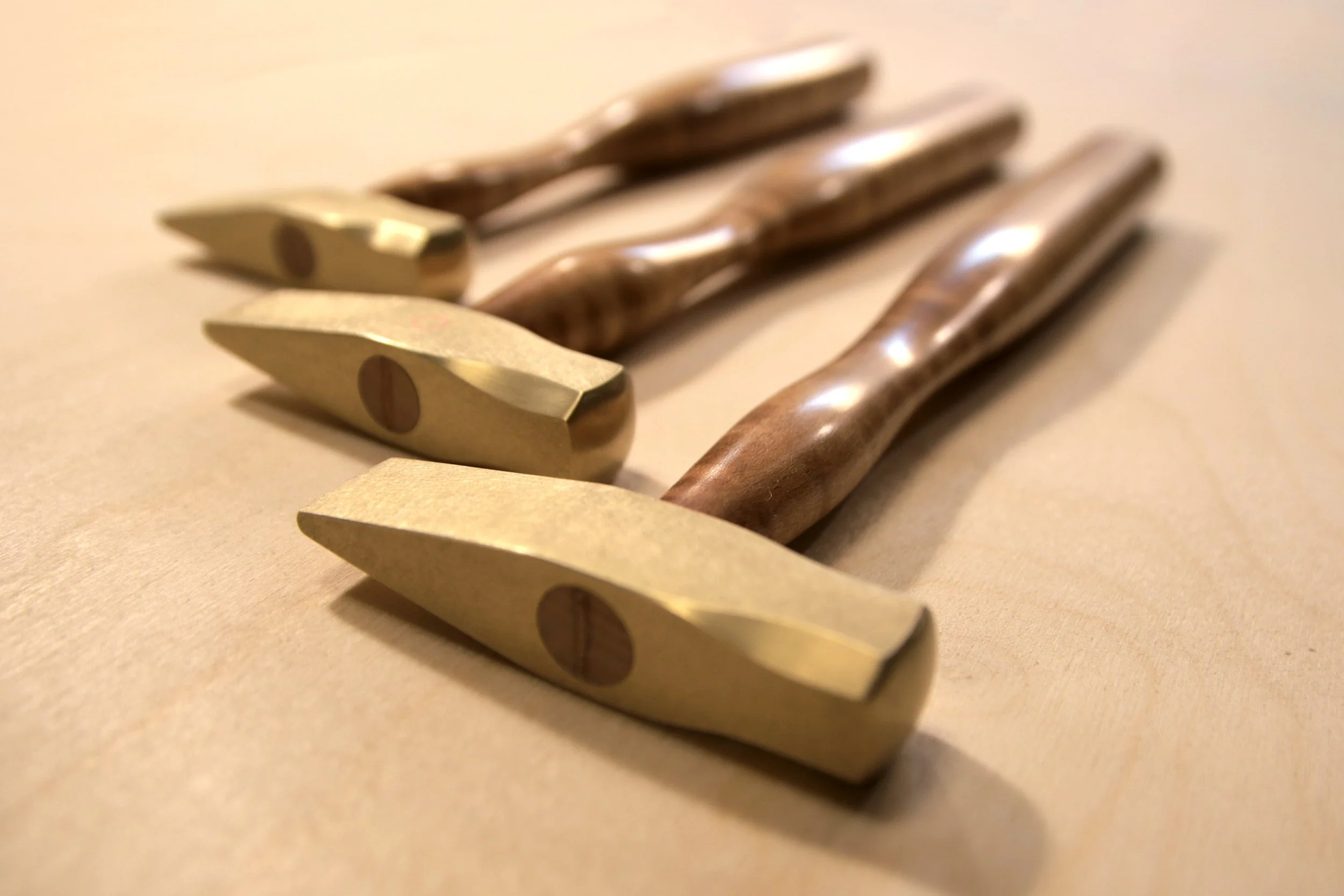 Three brass hammers with curly maple handles.