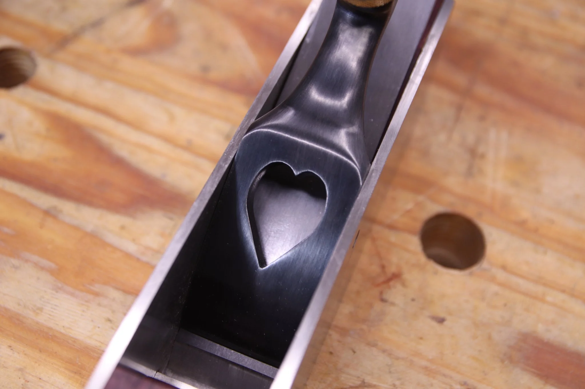 Close up of a lever cap for a miter plane. The lever cap has a heart shape cut into it. 