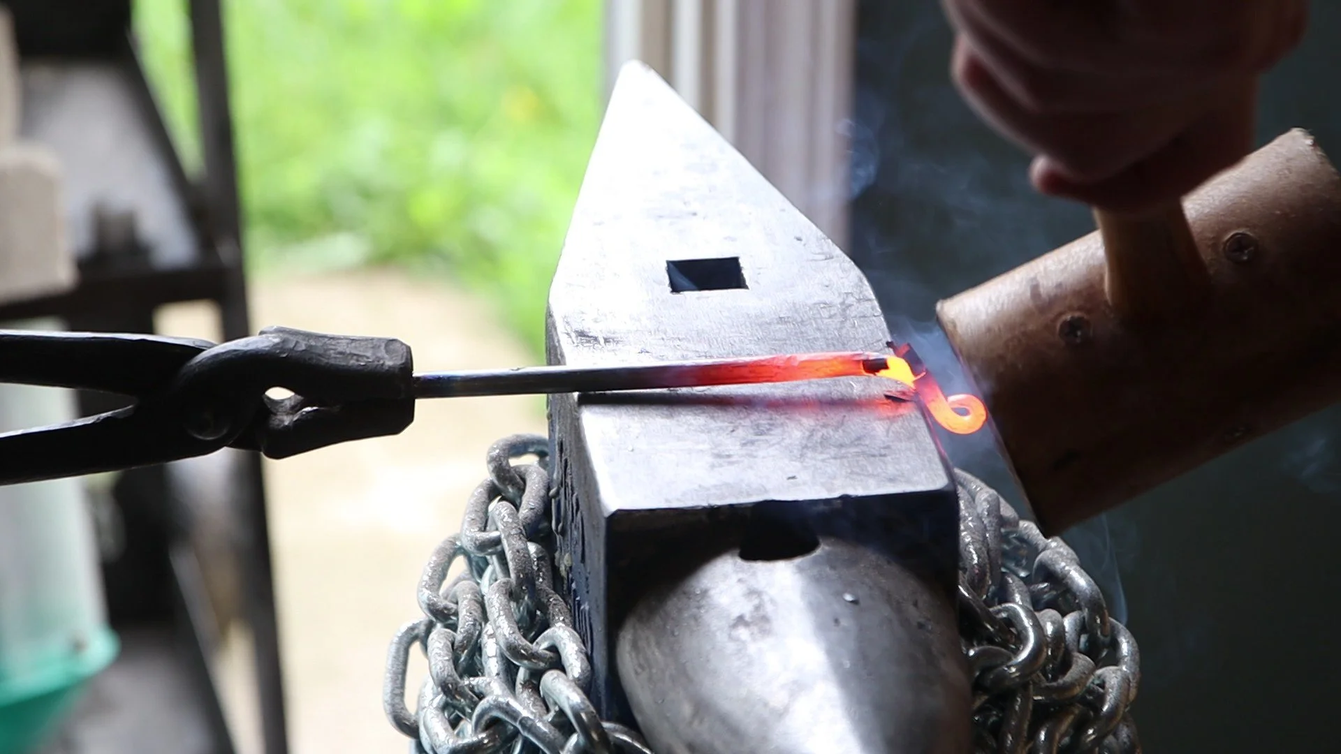 Forging a curl tip in a piece of round bar using a hammer and tonges 