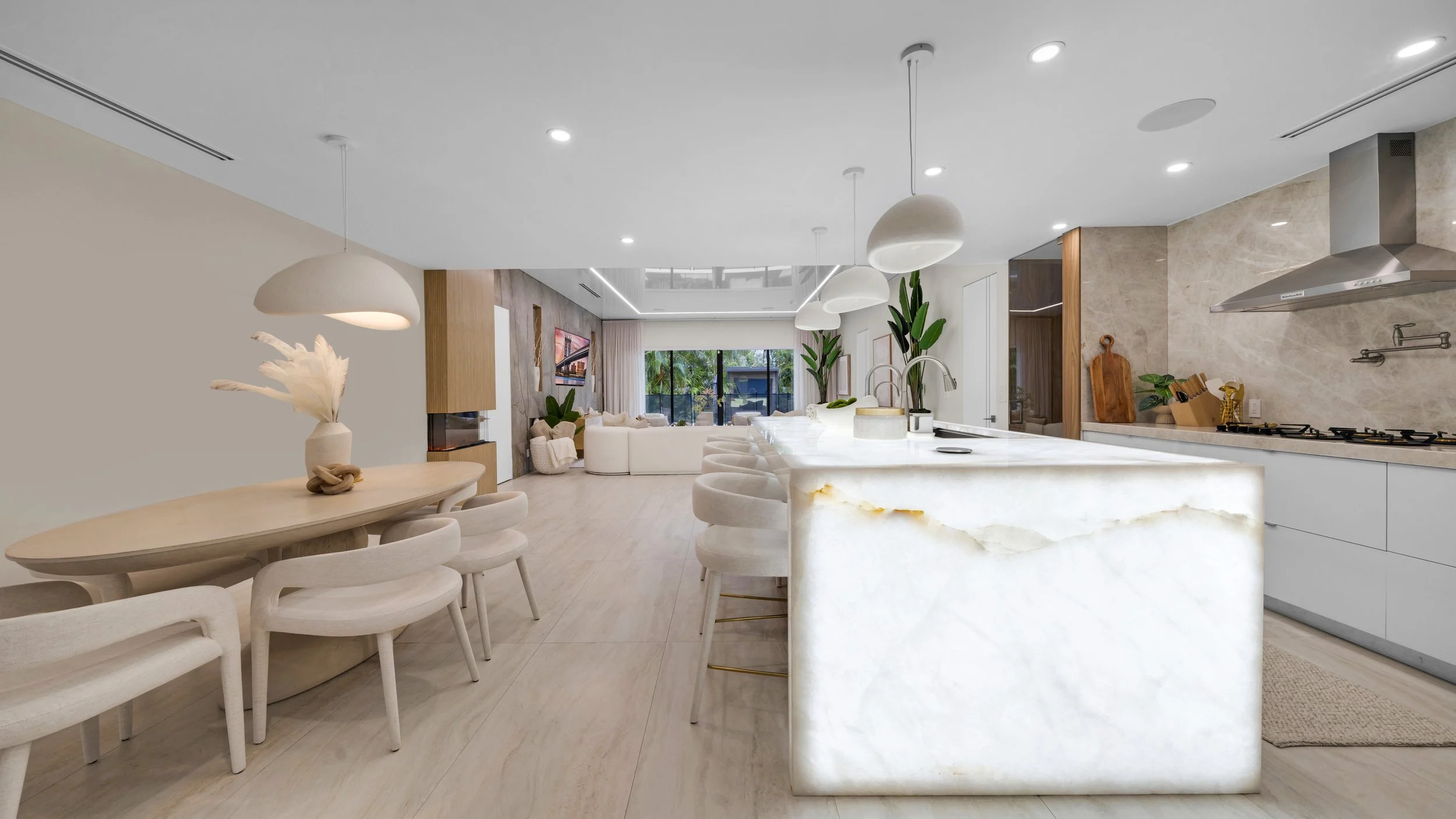Modern open-concept living space with a kitchen, dining area, and living room featuring neutral tones, minimal decor, and natural light.