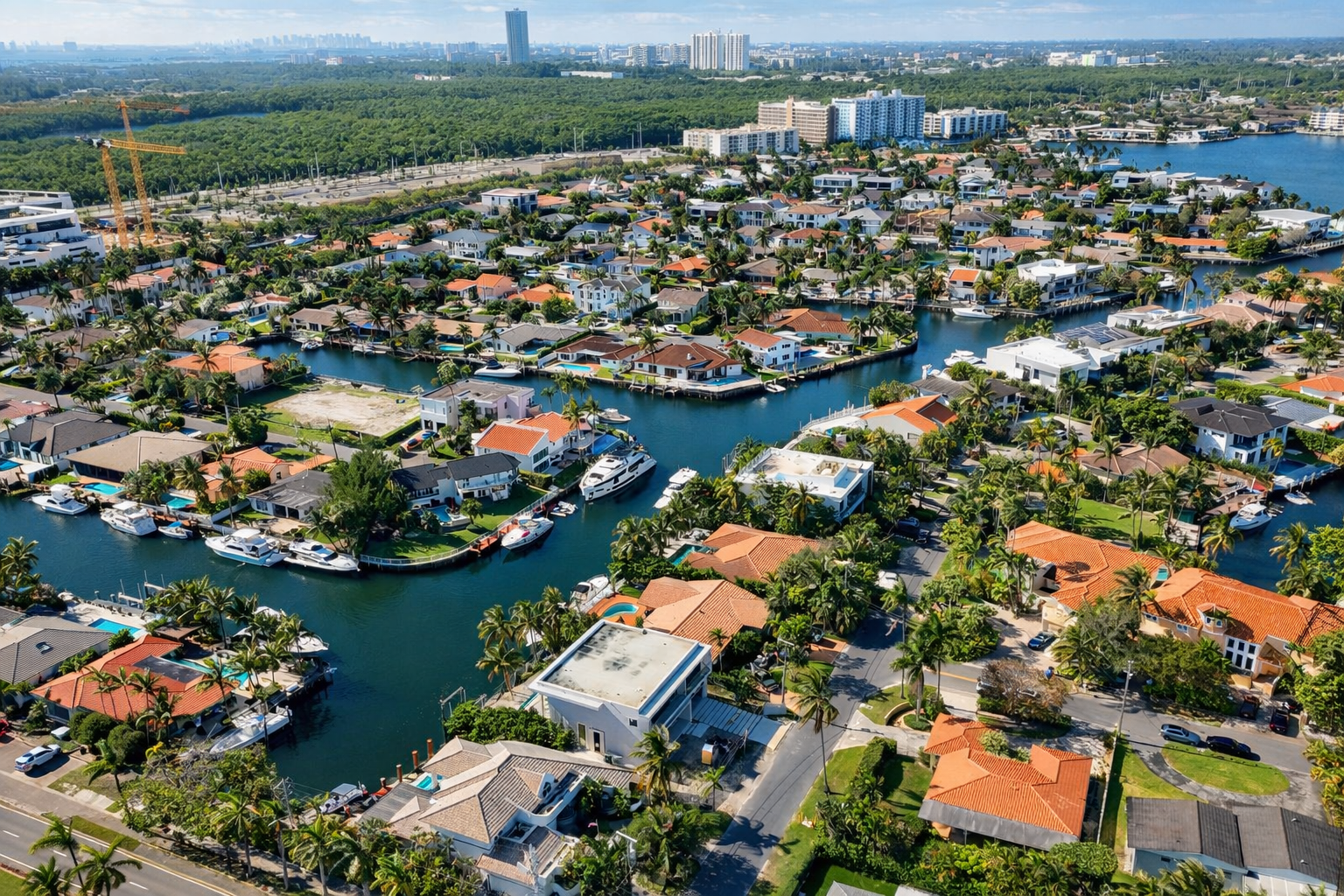 Aerial view of a coastal neighborhood with waterfront houses, boat docks, and lush greenery.