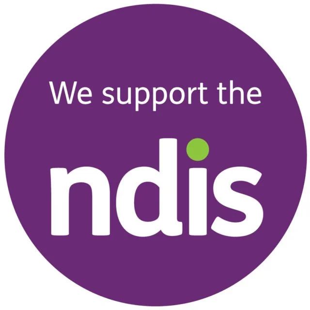 Purple circular logo with white text that reads "We support the ndis" and a small green dot over the letter "i".