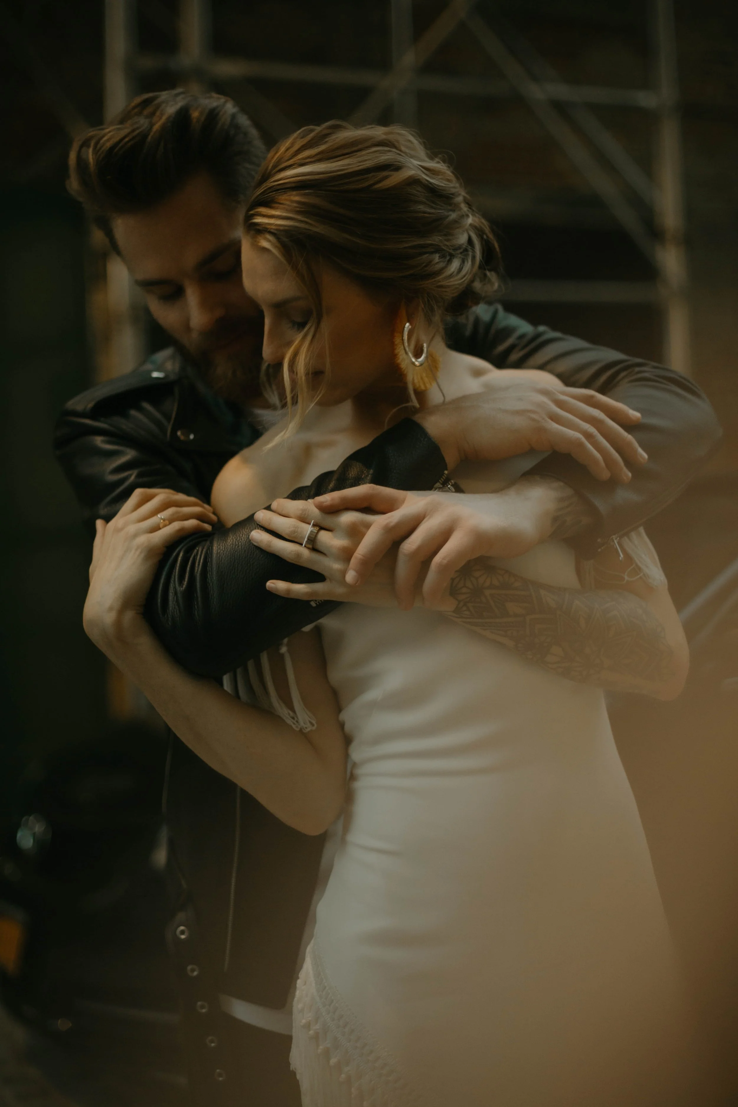 A pair of white high-heeled shoes with tulle bows, hanging on a green tree branch.