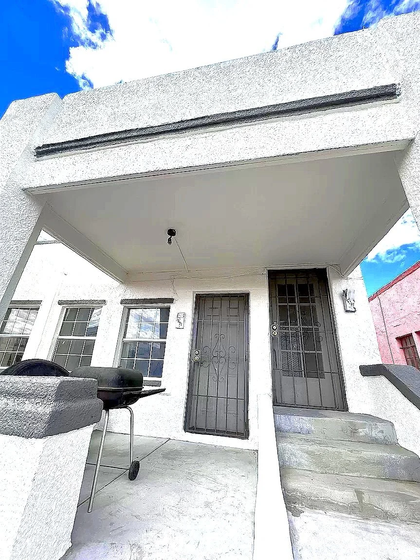 Front porch with a grill, two metal doors, and a small flight of stairs.