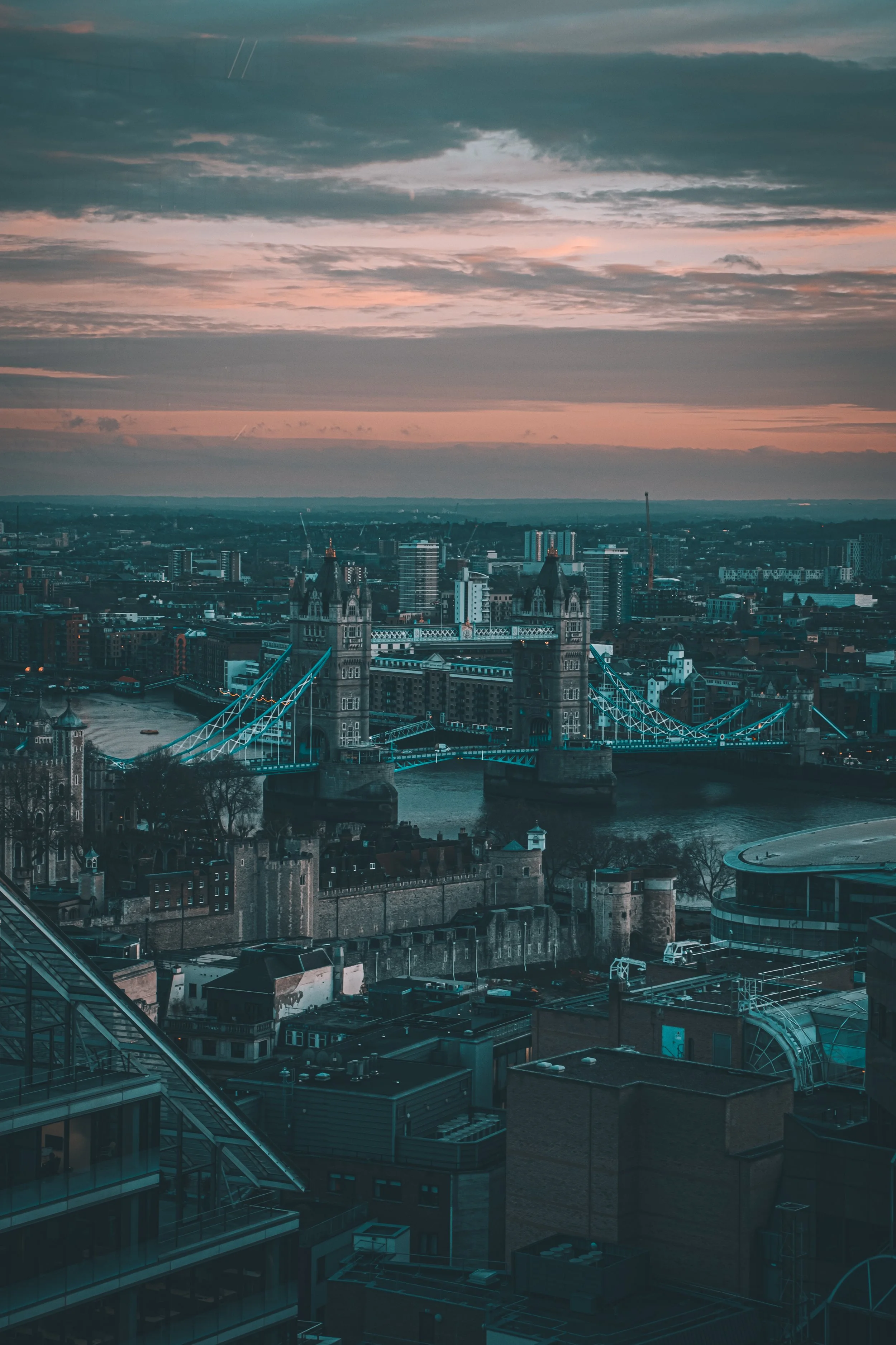 View of London skyline at sunset with Tower Bridge in the foreground.