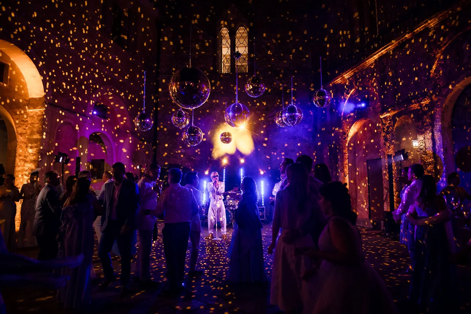 A band is performing in the courtyard of a Tuscan castle with the guests amazed by the enchanting atmosphere of lights created by the mirror balls