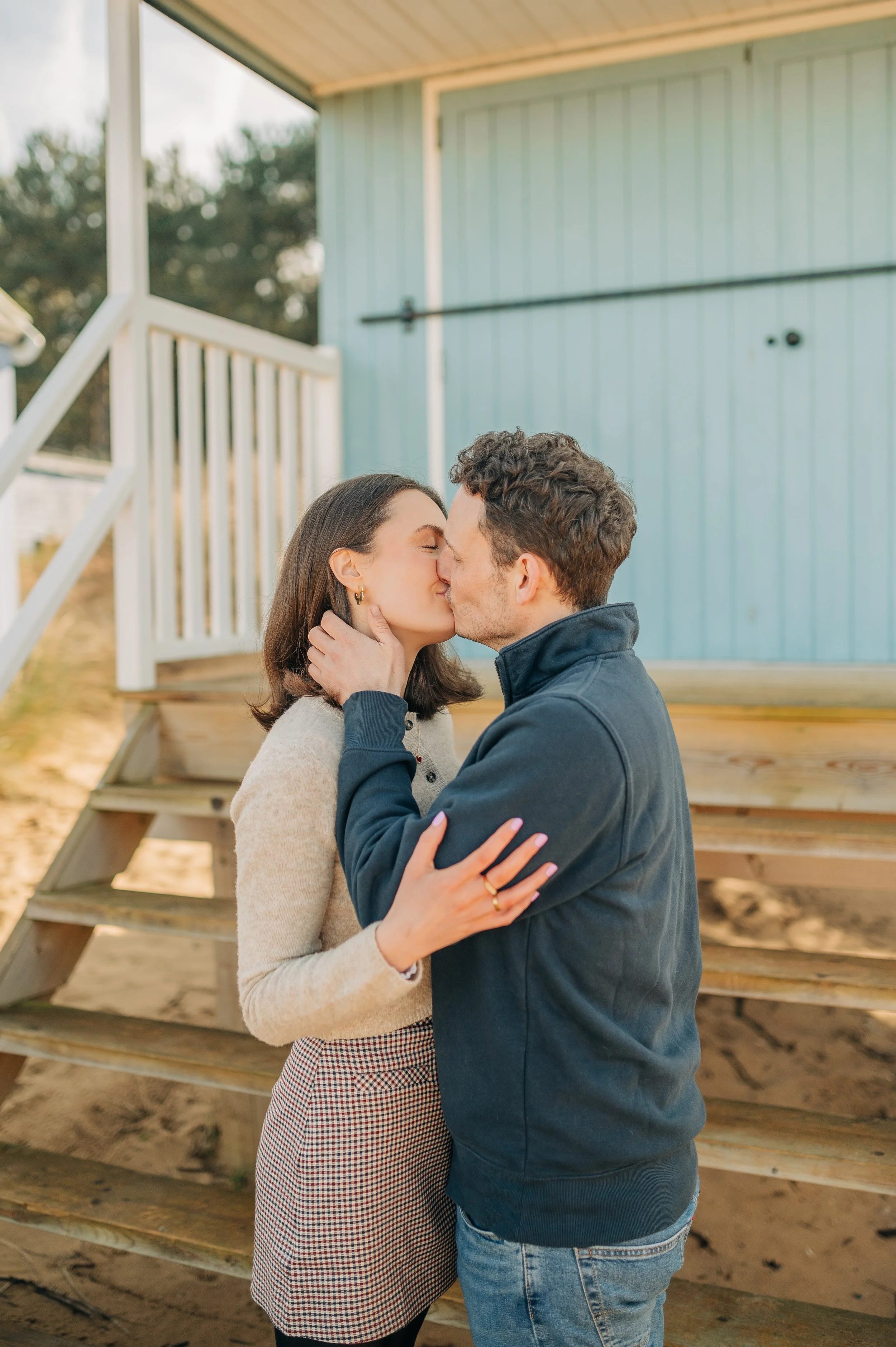 Norfolk Wedding Photographer.  A couple kissing in front of a blue house on porch stairs.