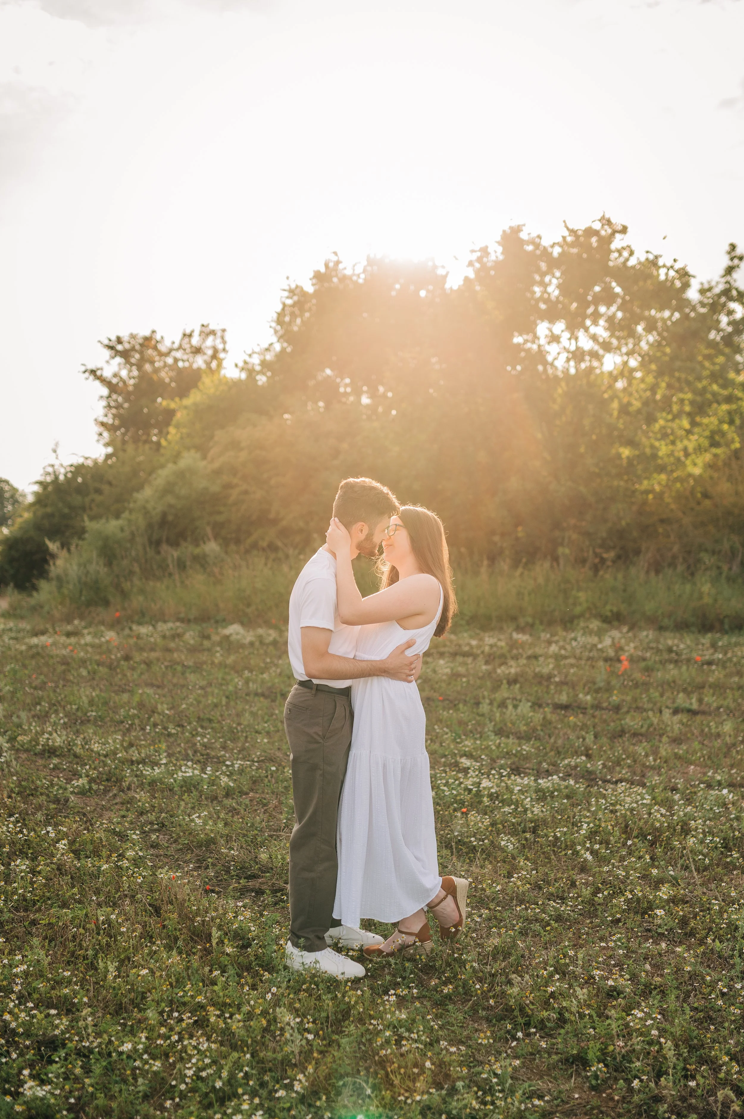 Norfolk Wedding Photographer.  A couple stands close together in a field during sunset, embracing and gazing into each other's eyes.