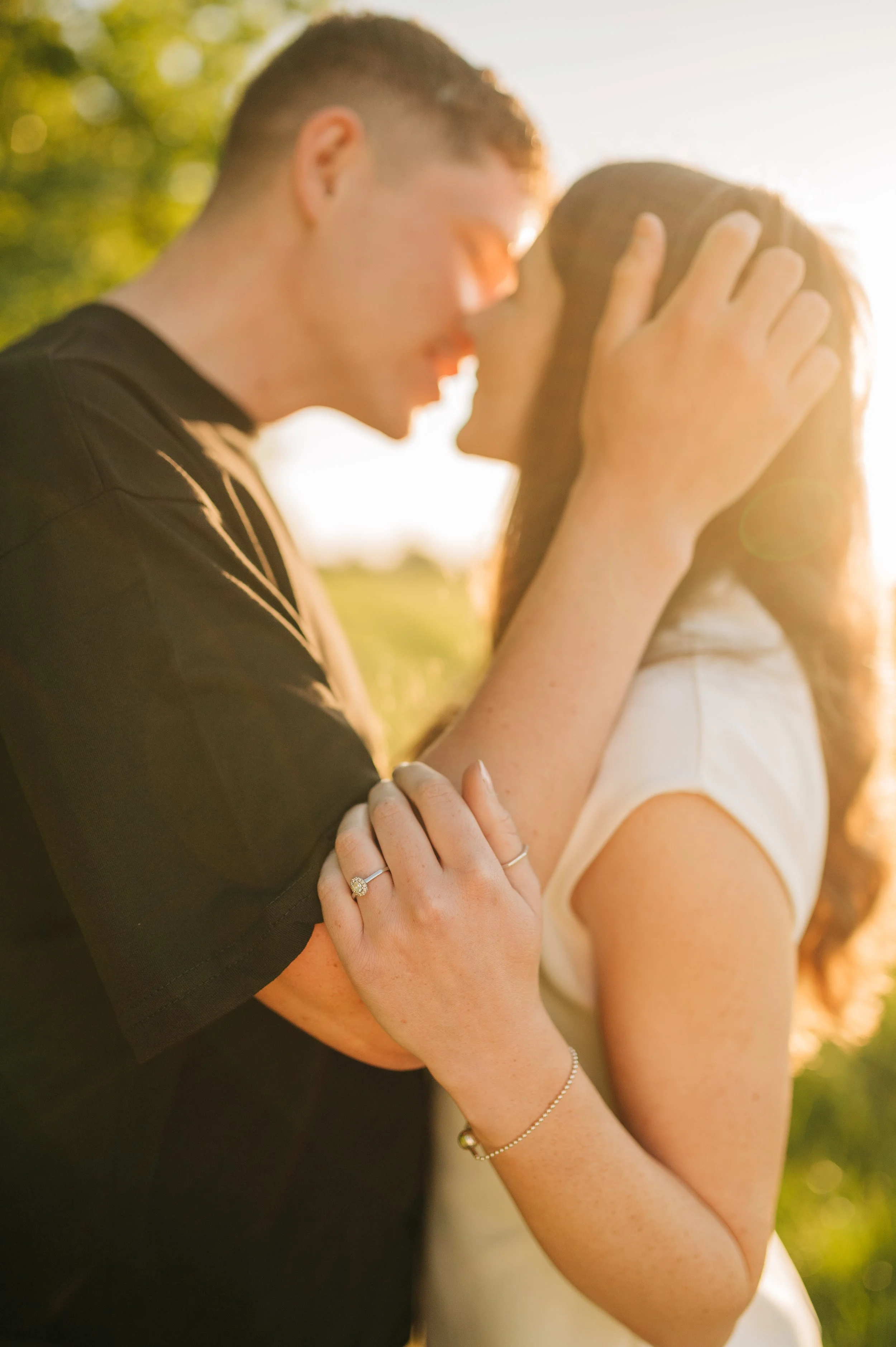 Norfolk Wedding Photographer.  A couple sharing an intimate moment outdoors during sunset, with their faces close and hands gently touching, with a focus on their jewelry.