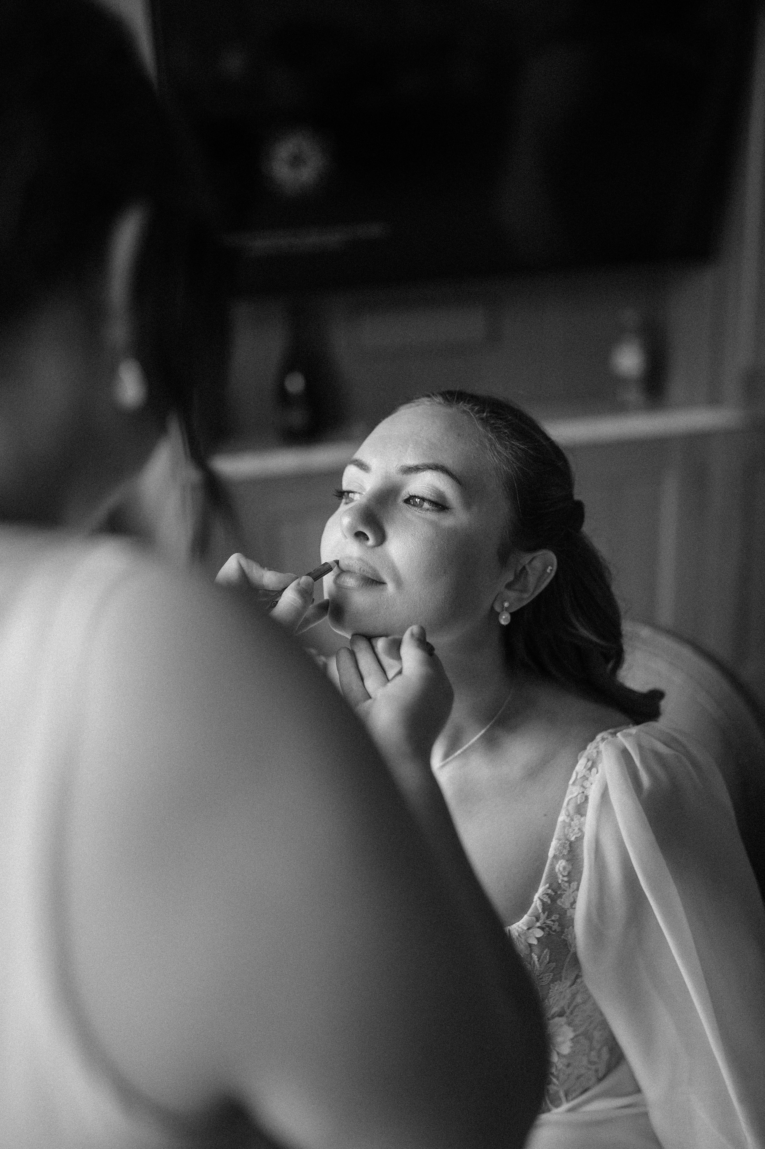 Norfolk Wedding Photographer. Woman gets her makeup applied by a makeup artist in a black and white photo.