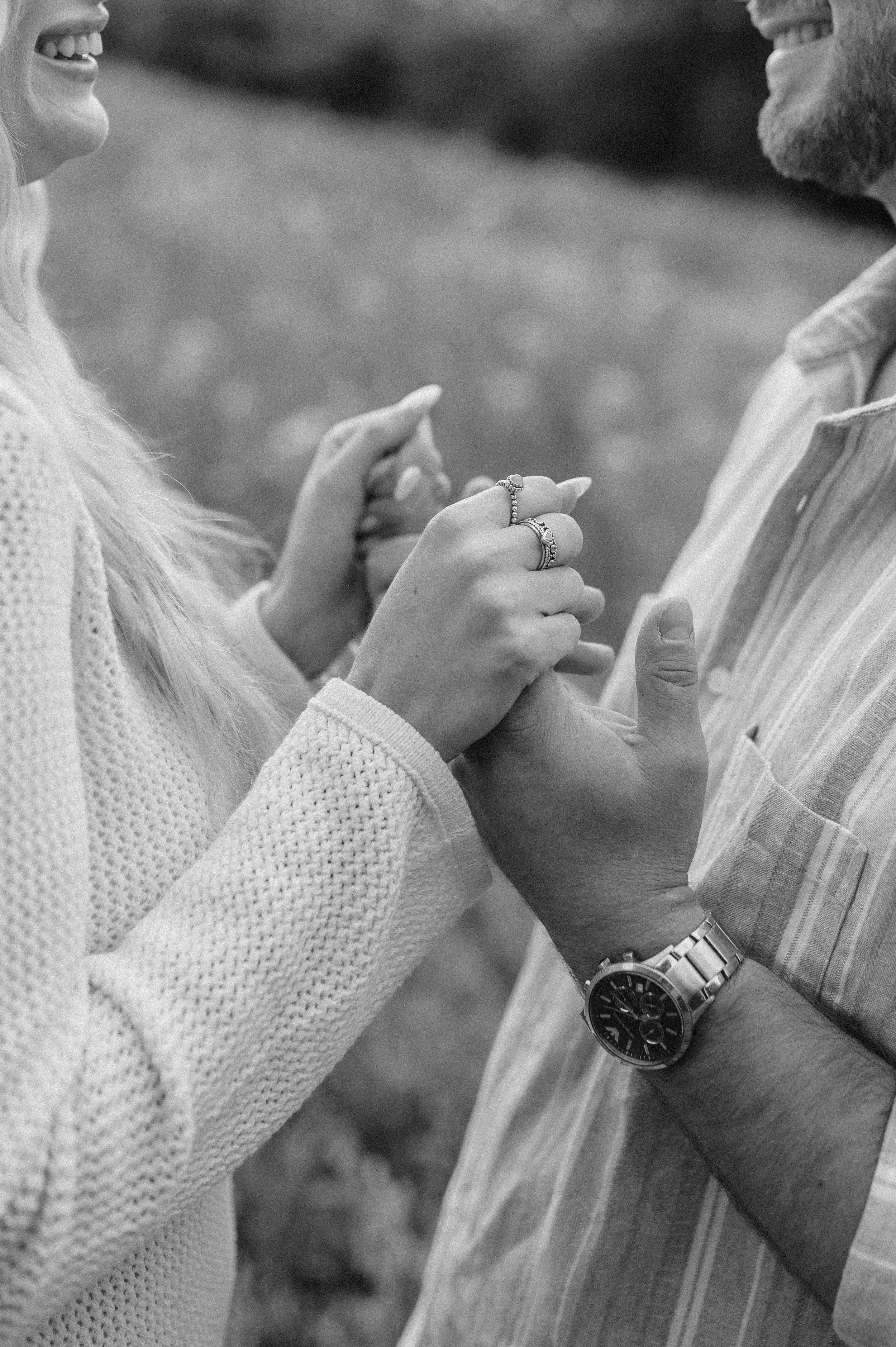 Norfolk Wedding Photographer.  A couple holding hands, with the woman wearing multiple rings and the man wearing a watch, as they smile at each other.