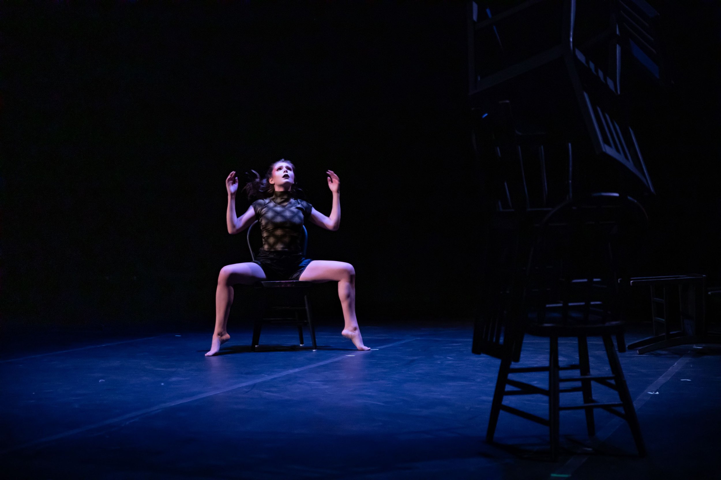 katie hileman is falling back into a chair while gazing in fear at a tower of chairs perched precariously before her