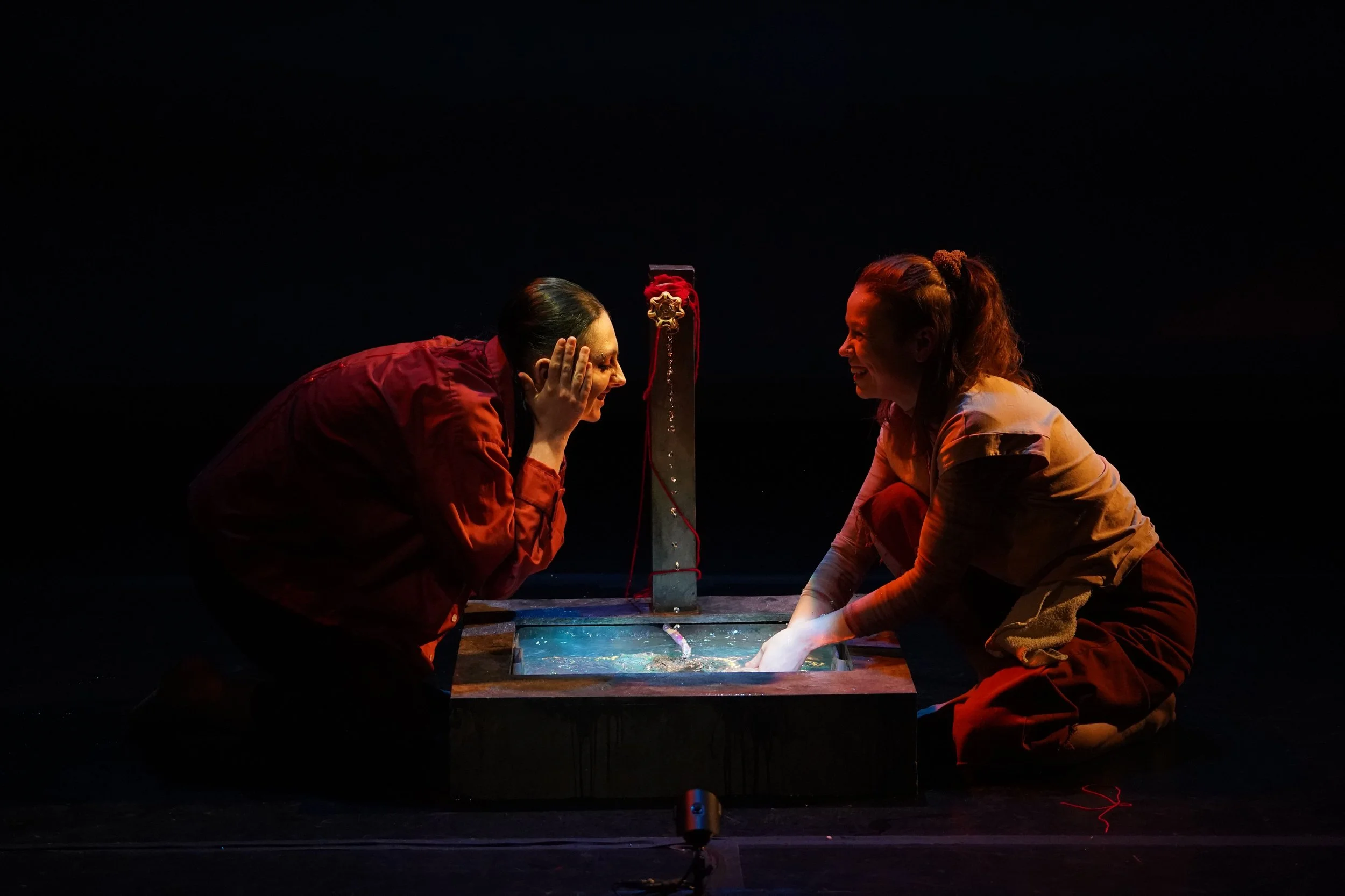 duet. willow and ari kneel by the waterstation. Willow rubs water against their face while ari laughs