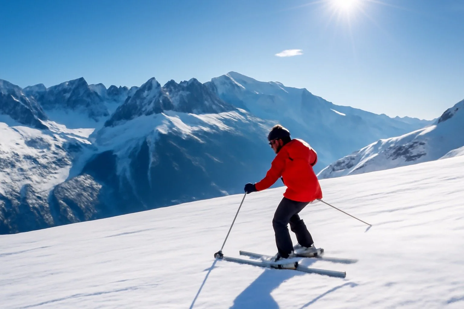 Skier on snowy slopes with alpine peaks in the background
