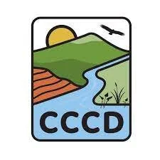 Logo with landscape depicting sun, green hills, river, and a bird in the sky, over the letters CCCD.