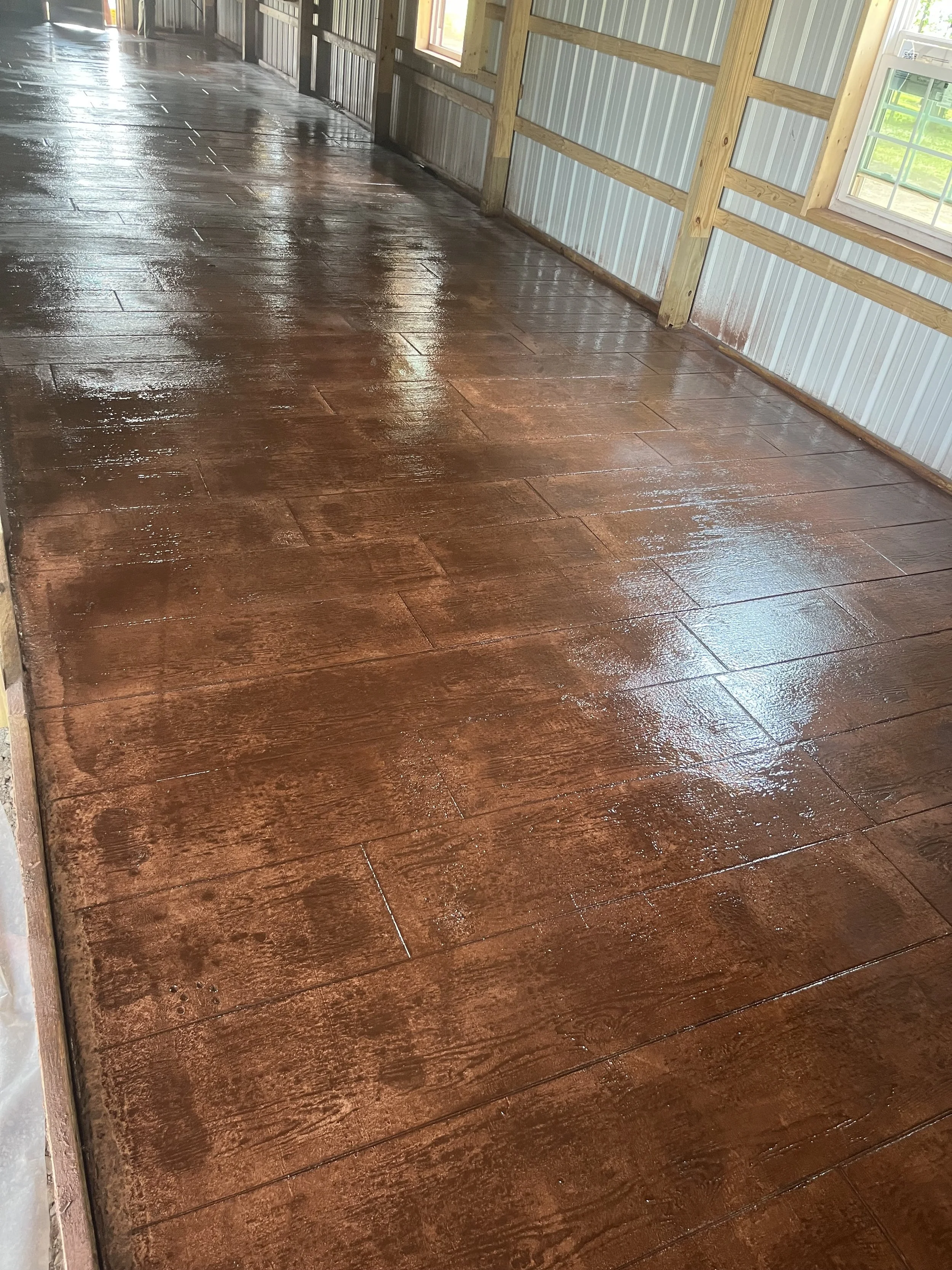 Shiny wet wooden floor in a partially enclosed structure with metal siding and windows.