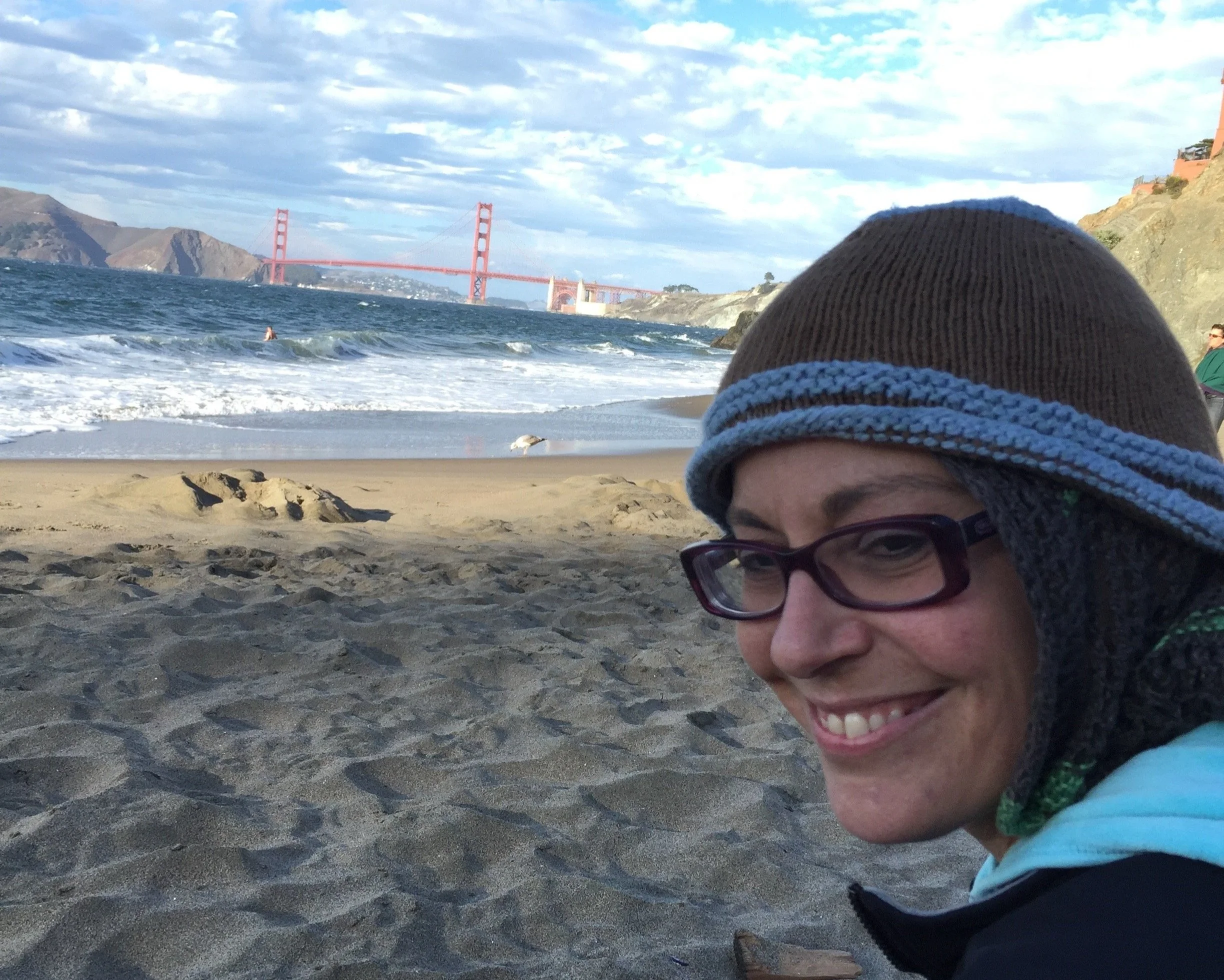 Sarah smiling at China Beach in San Francisco with Golden Gate Bridge in background