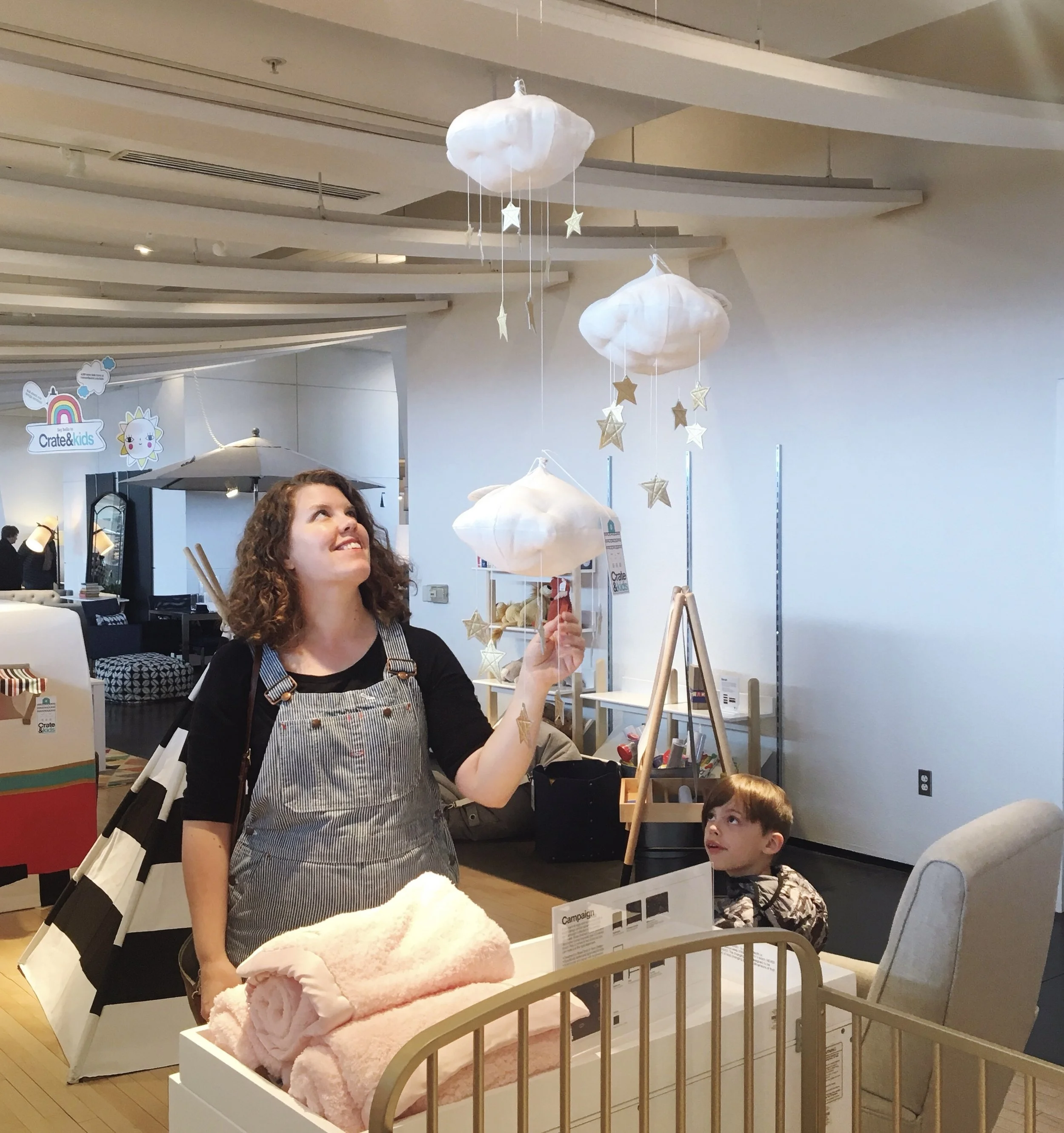 A woman and a young boy at a store display with hanging cloud and star decorations.