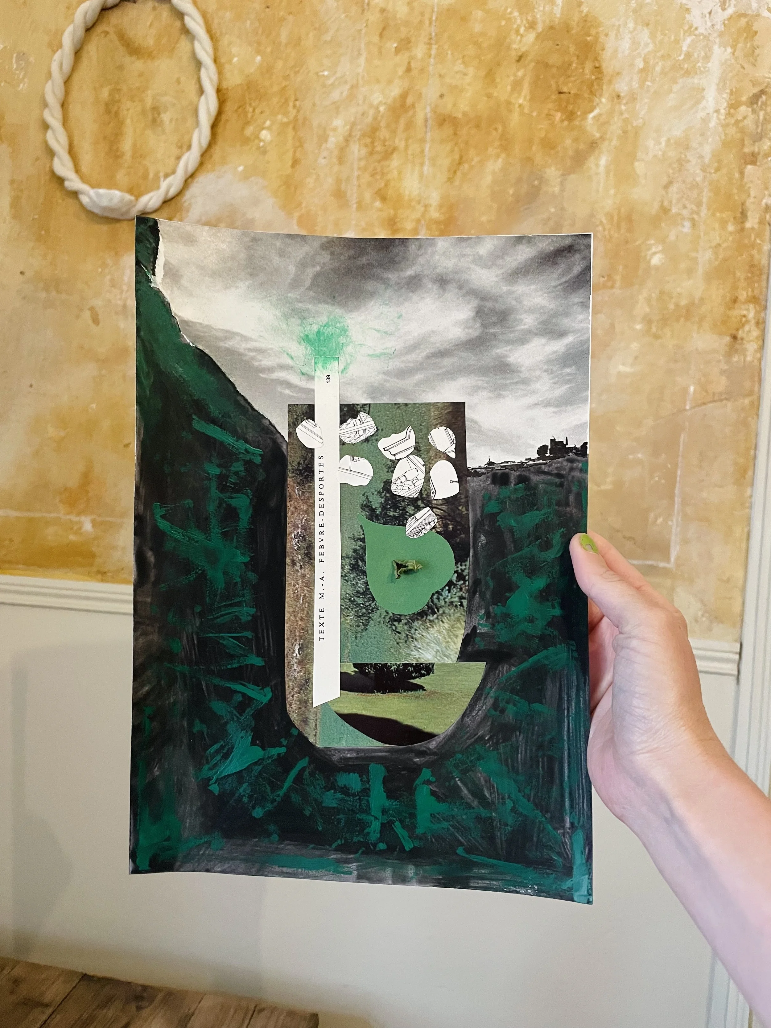 A photo of a hand holding up a mixed media collage of green paint, vintage magazine imagery. The collage is of a mint drink, featuring teeth shaped ice cubes, in front of a stormy sky.