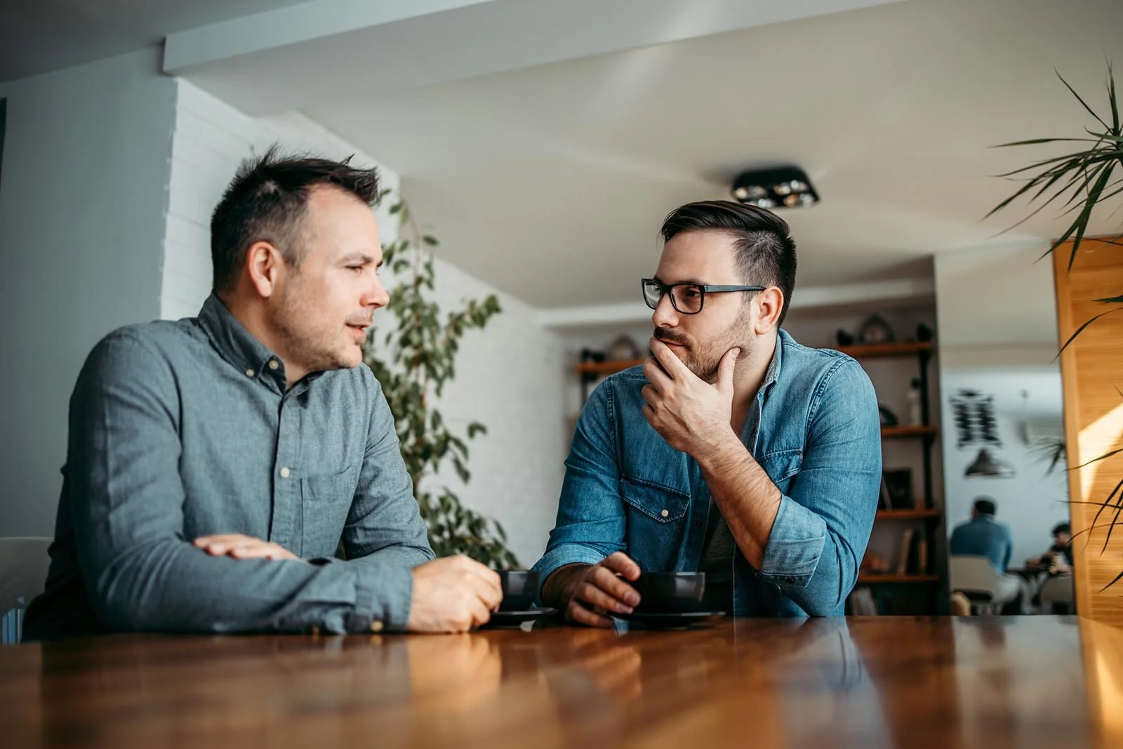Two colleagues listening and talking across a table.