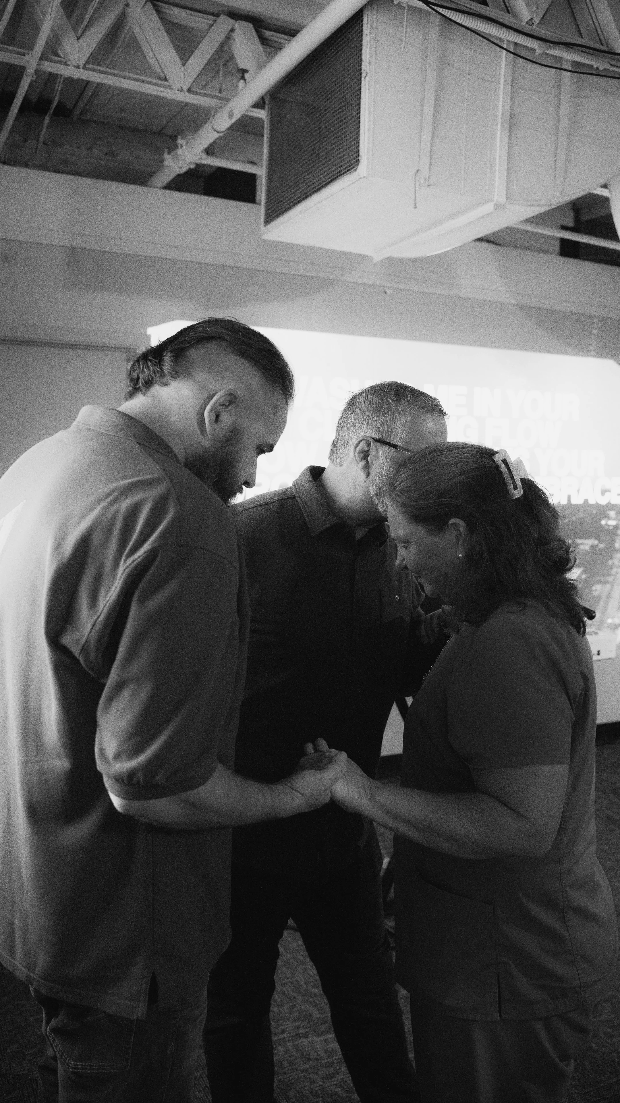 Three people in prayer during a church service.
