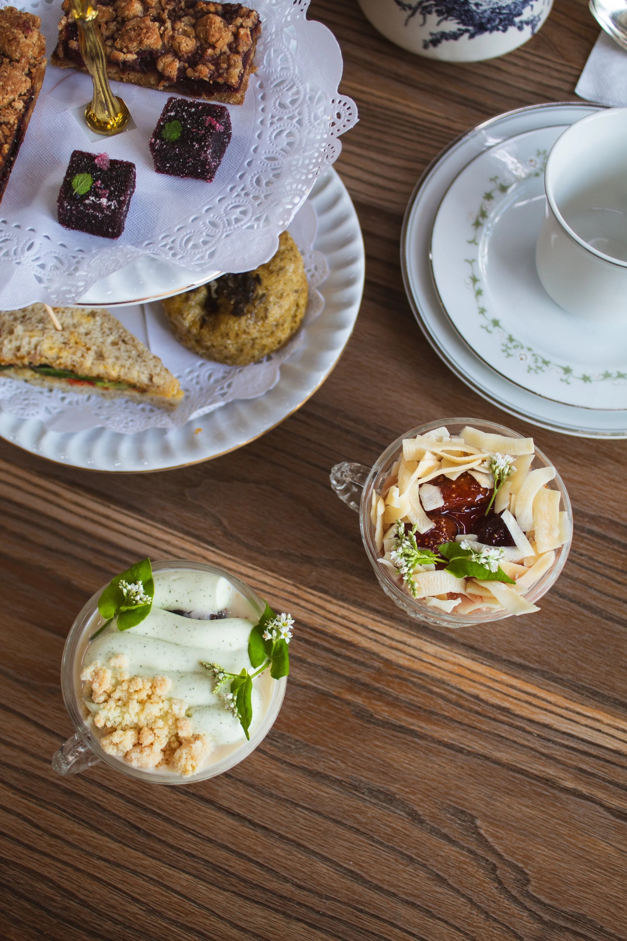 Various small desserts including a slice of cake with sprinkles, a cookie with white icing, and other assorted pastries on a two-tiered gold and white serving tray for a Florosa tea party.