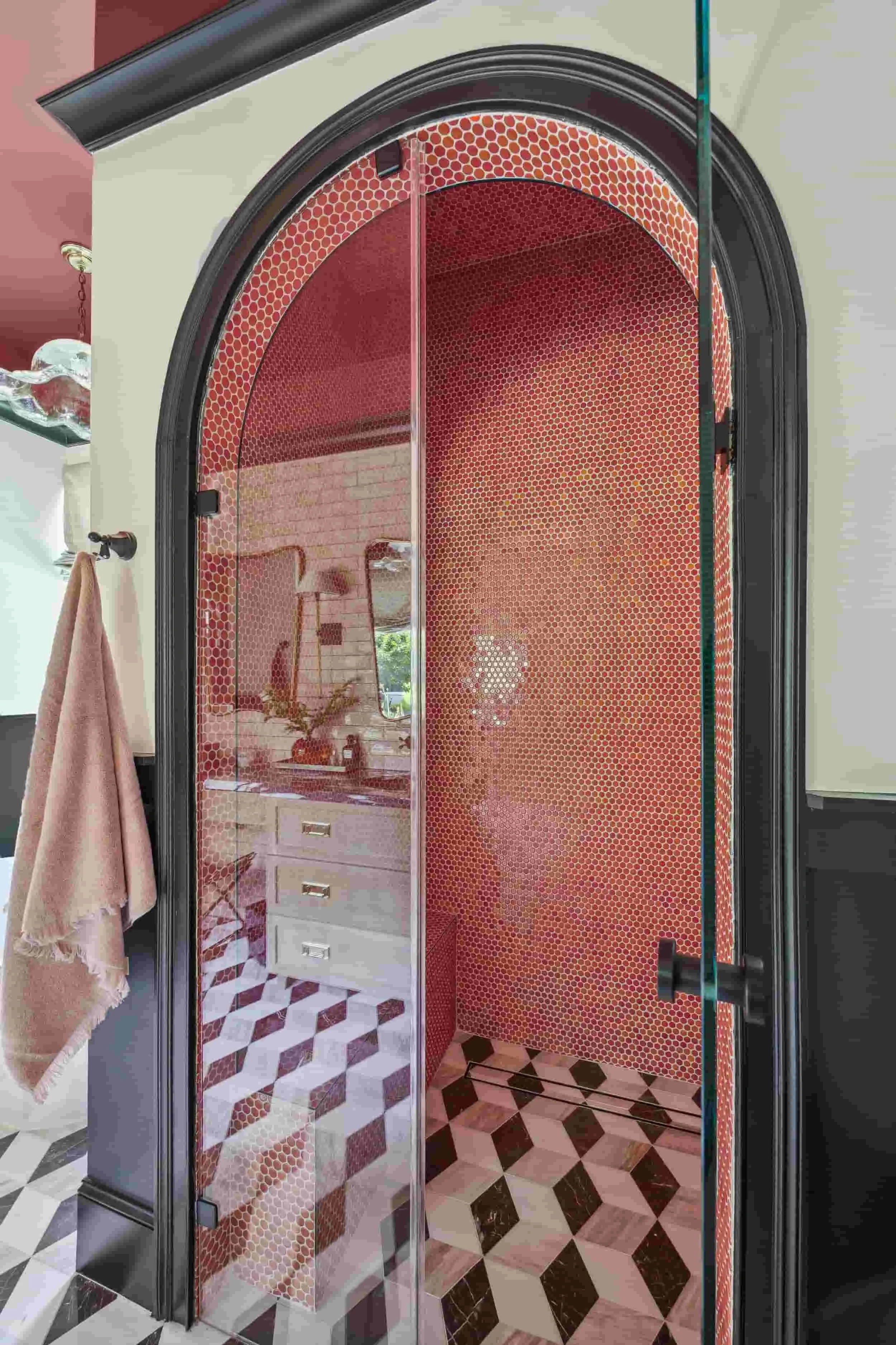 Vintage-style shower with glass doors, red mosaic tile walls, and honeycomb accents, with a patterned tile floor.