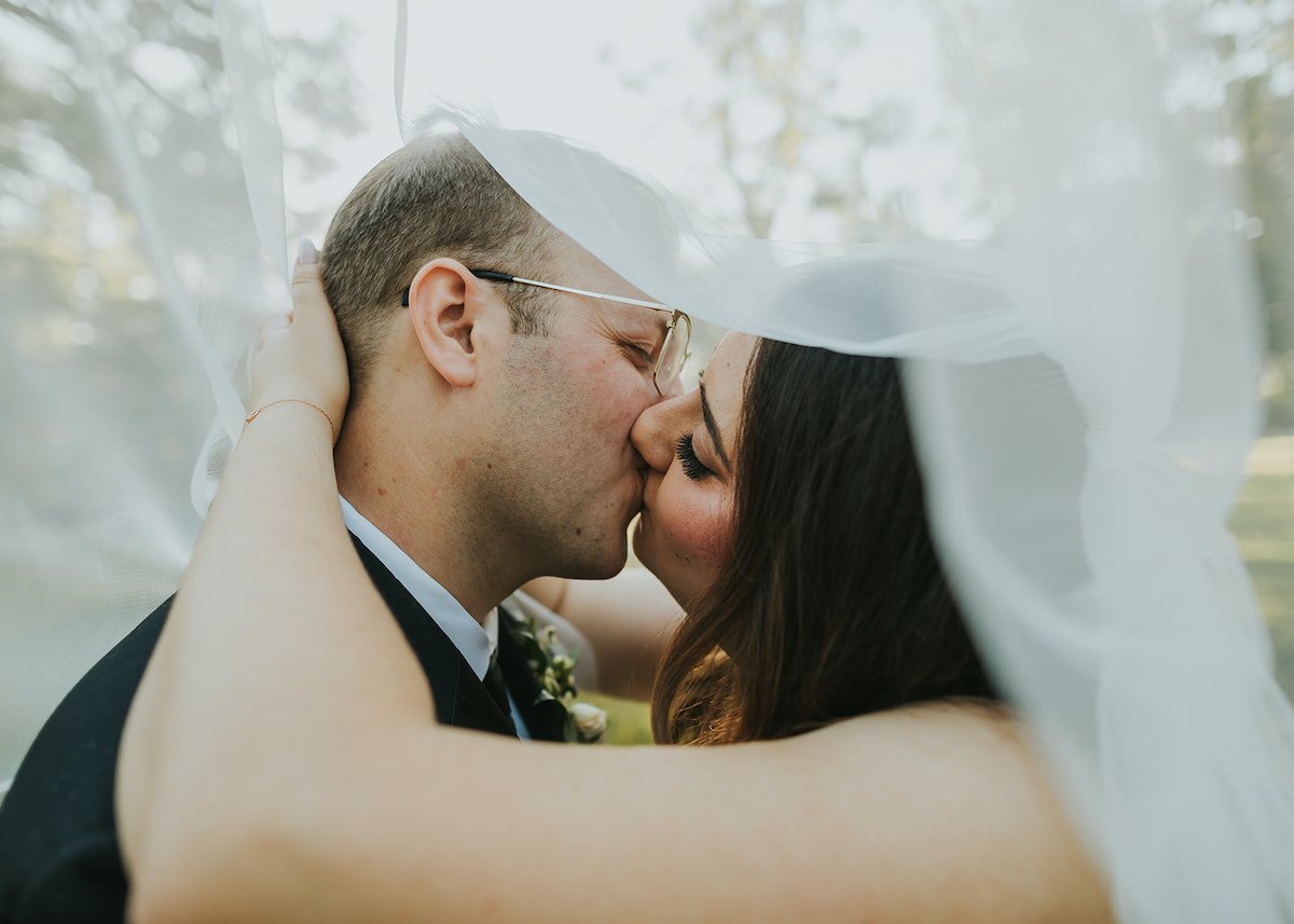  Bride and groom kissing underneath veil 