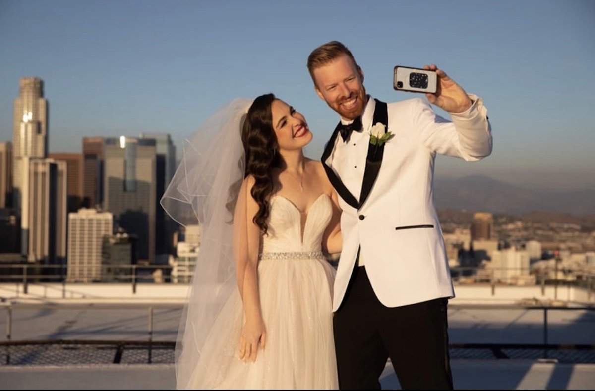  bride taking a selfie with husband in her hollywood waves hair and red lip 