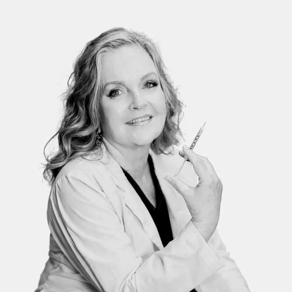 Black and white photo of a woman in a lab coat holding a syringe.