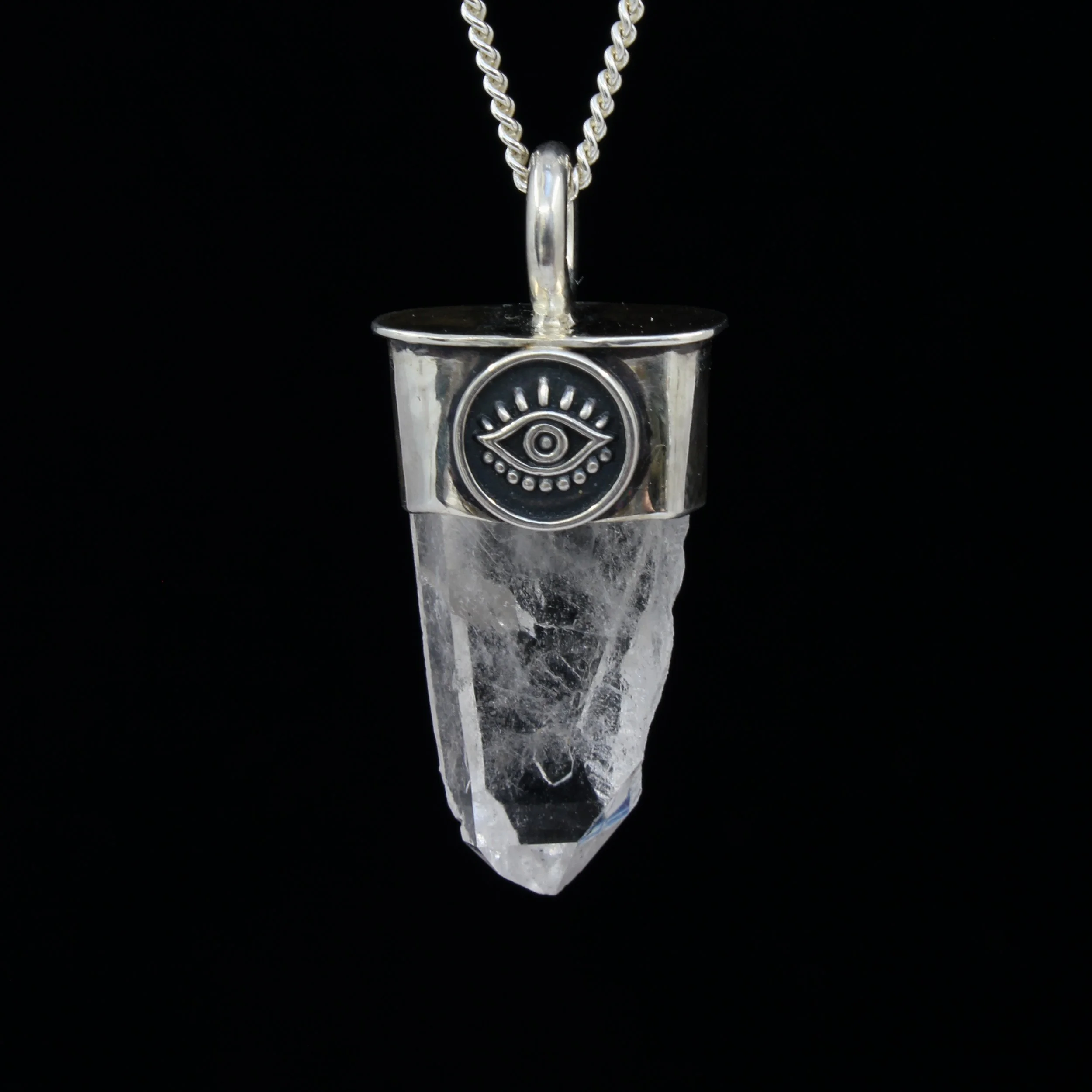 Sterling silver and raw quartz point pendant with an oxidised eye design on the silver and rough texture on the quartz. Pendant is hanging on a fine silver chain against a black background