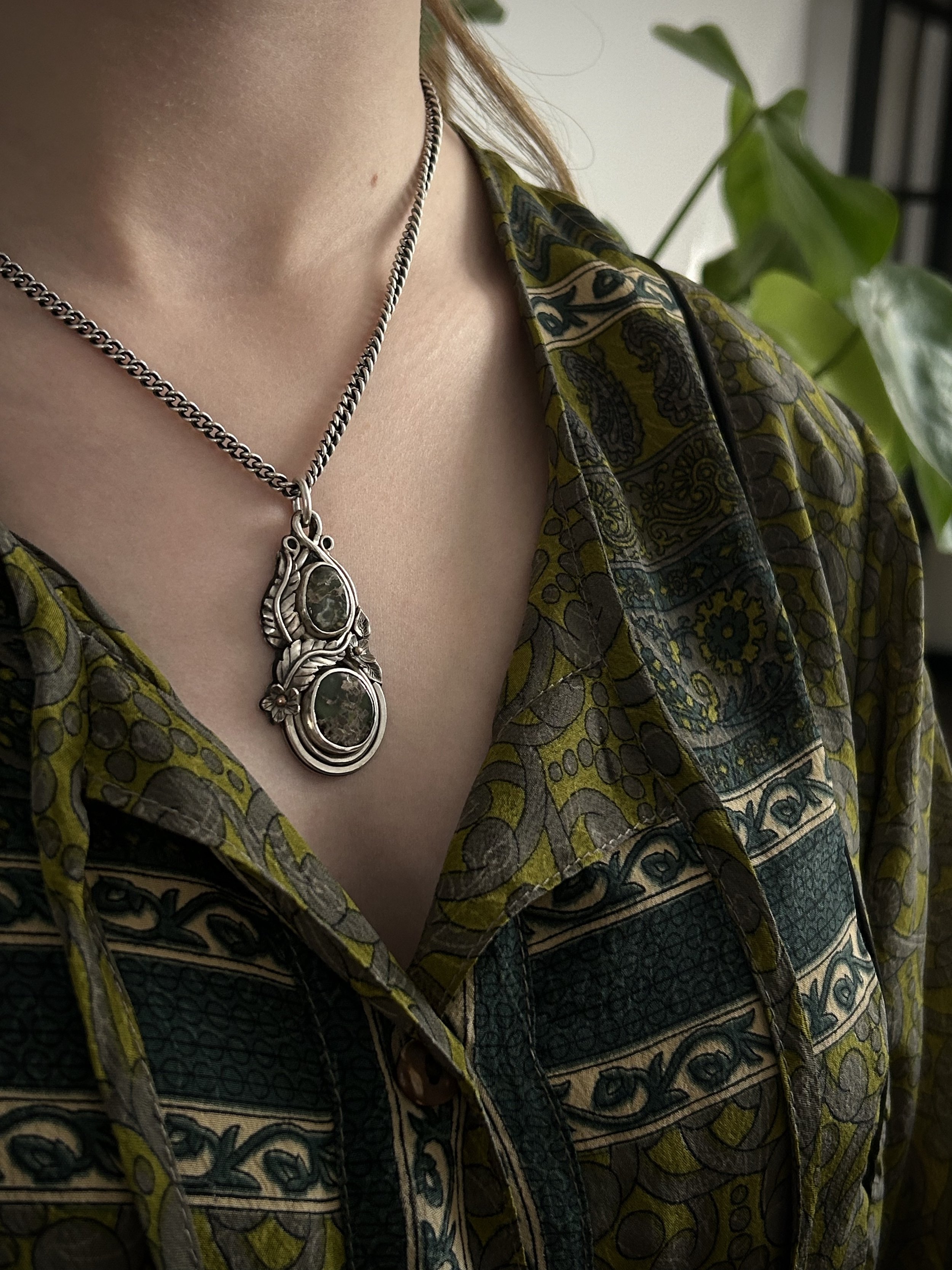 Model in green top wearing silver and green variscite floral pendant on a thick silver chain