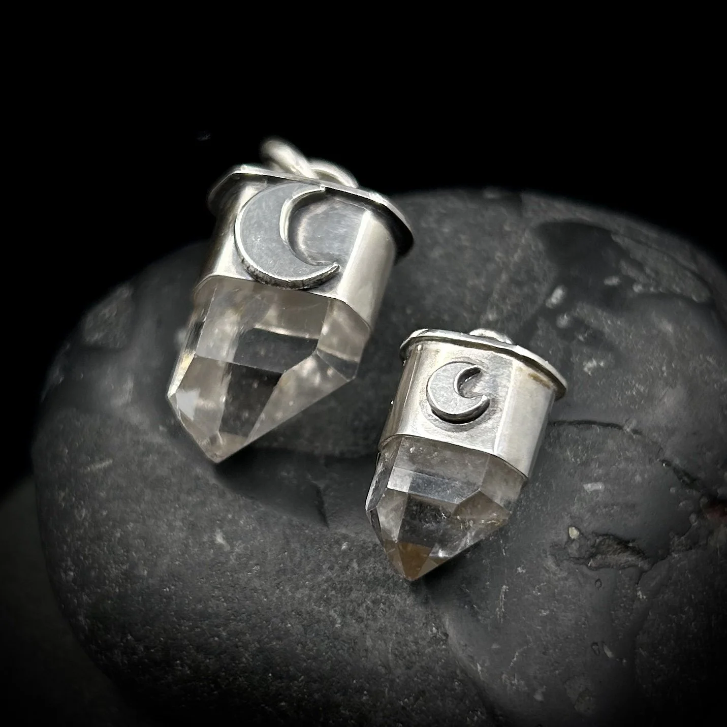 Side comparison between the small and mini waning crescent moon pendants, both are made from silver and feature a clear Tibetan quartz point