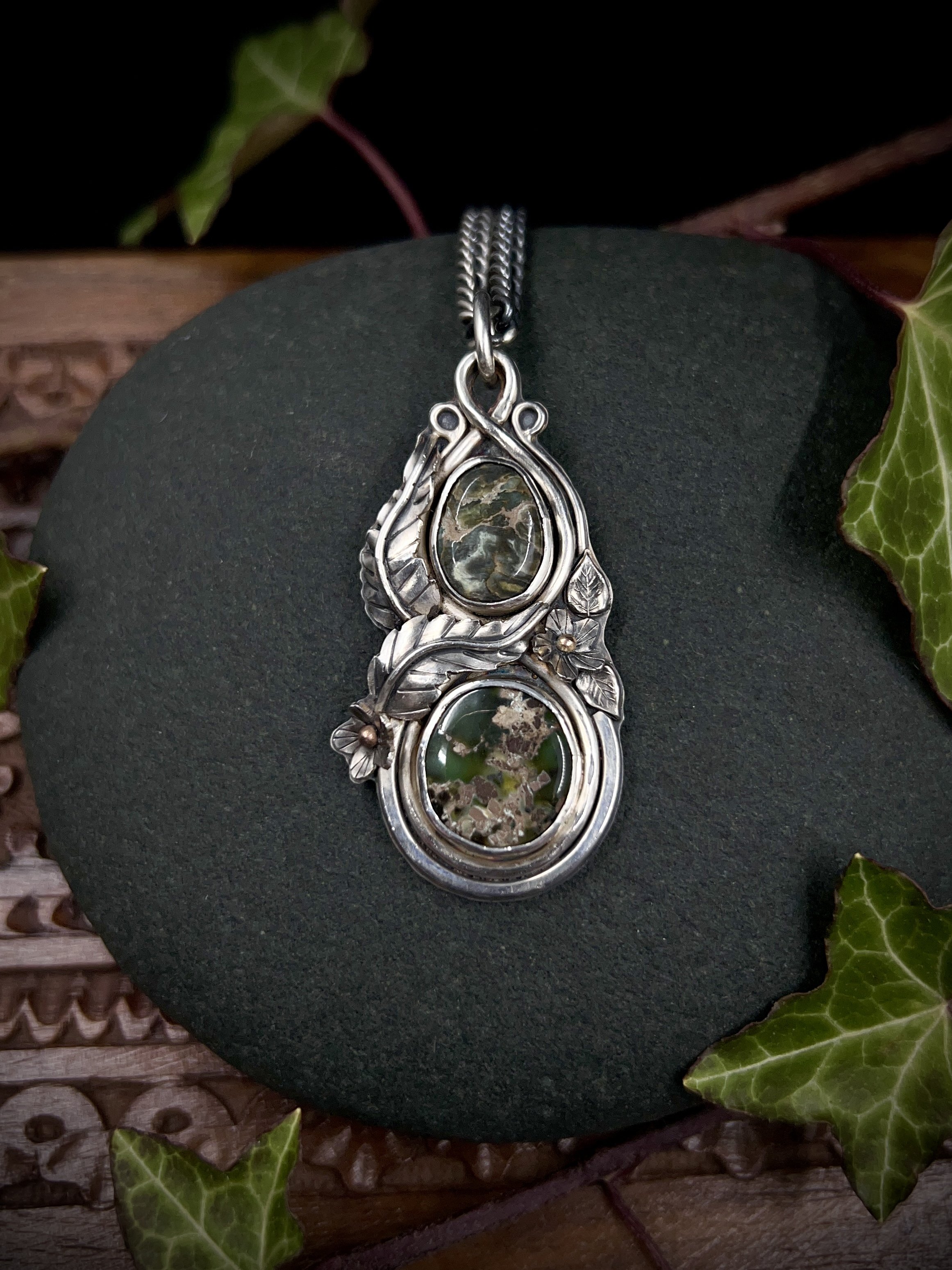 Front view of silver pendant showing two green variscite stones, one above the other, surrounded by silver leaves and flowers