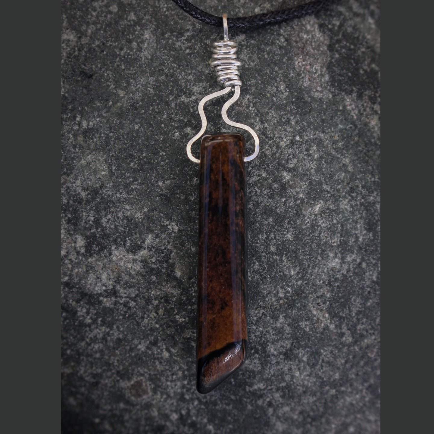 Front view of tiger’s eye stone showing brown chatoyant and silver flame wrapped detail