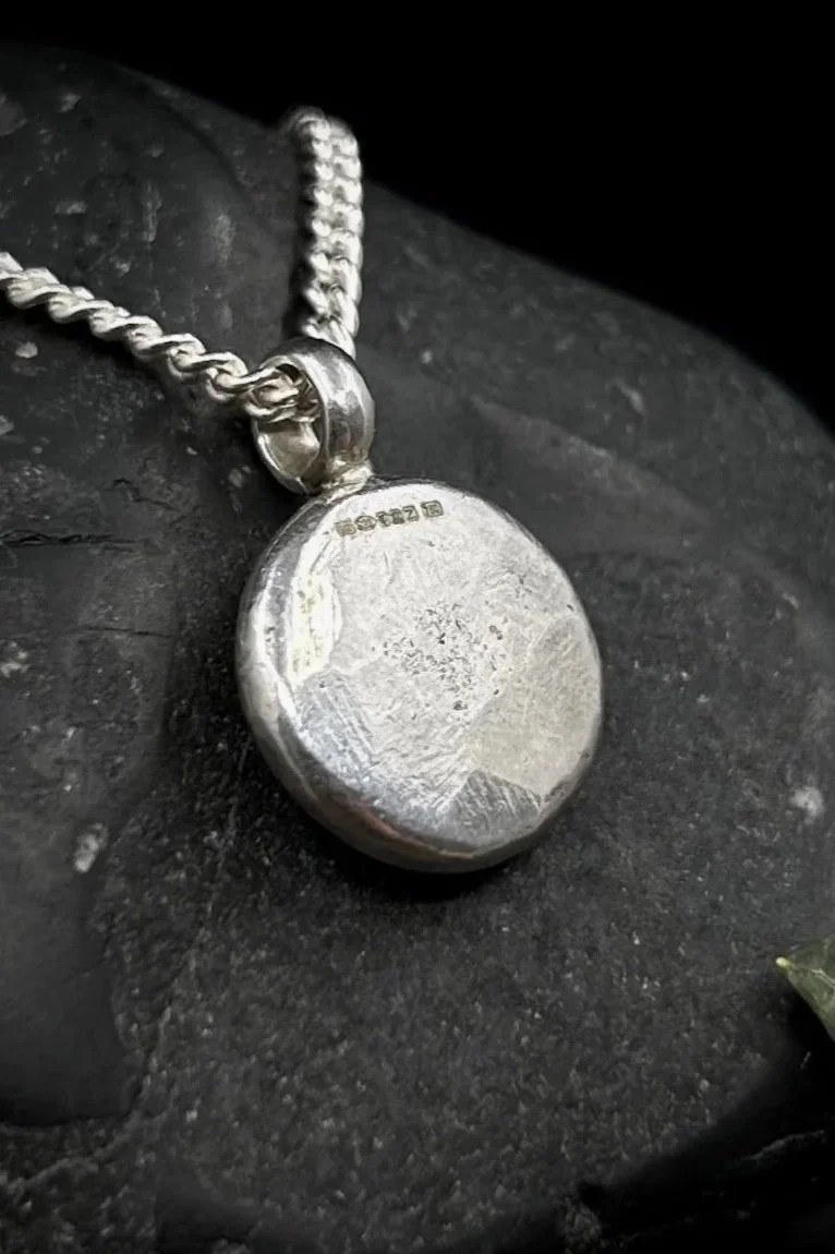 Close up of textured back of ancient goddess pendant in silver displaying a full hallmark for gold and silver