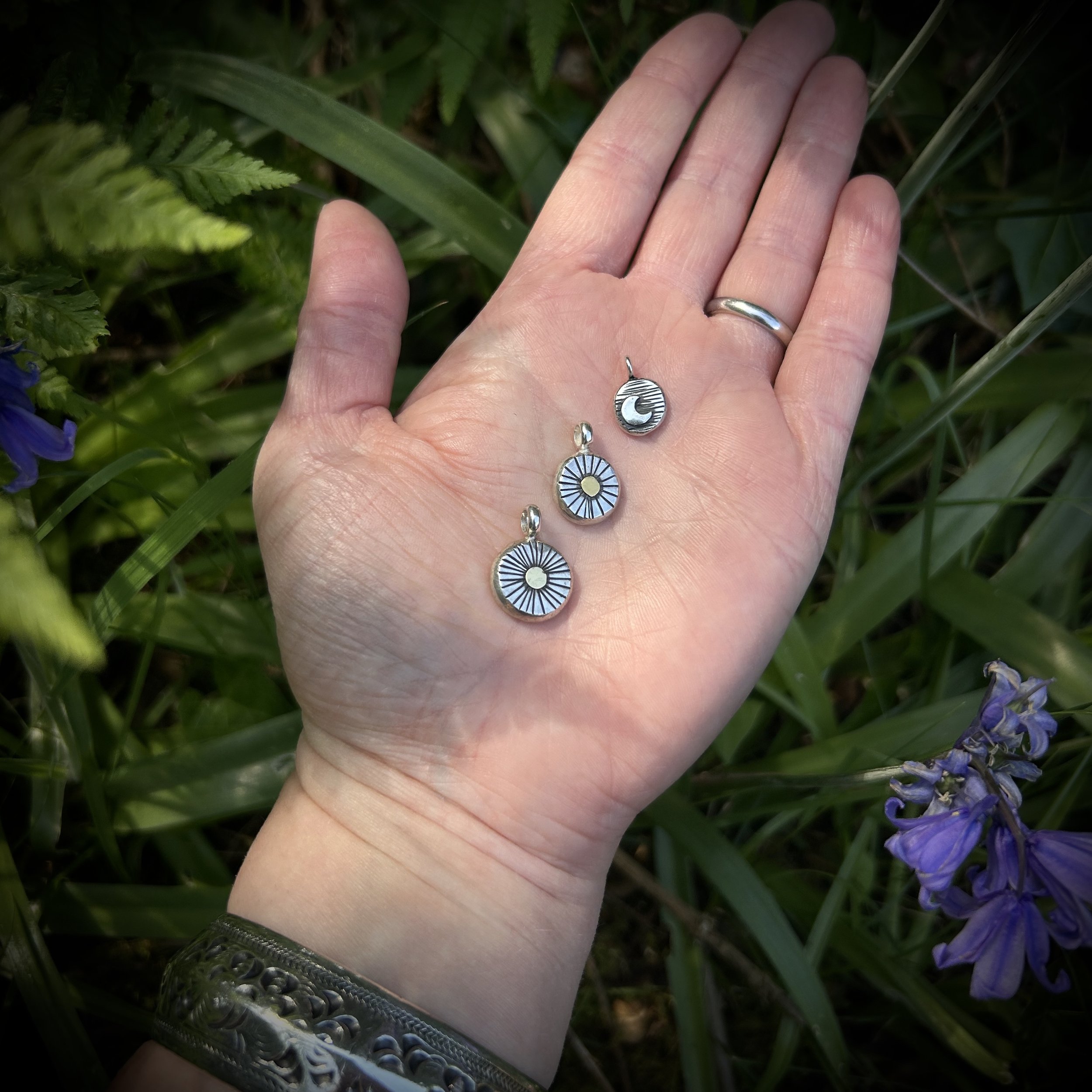Three pendants on model’s palm showing a scale between mini, small and medium sized pebble pendants