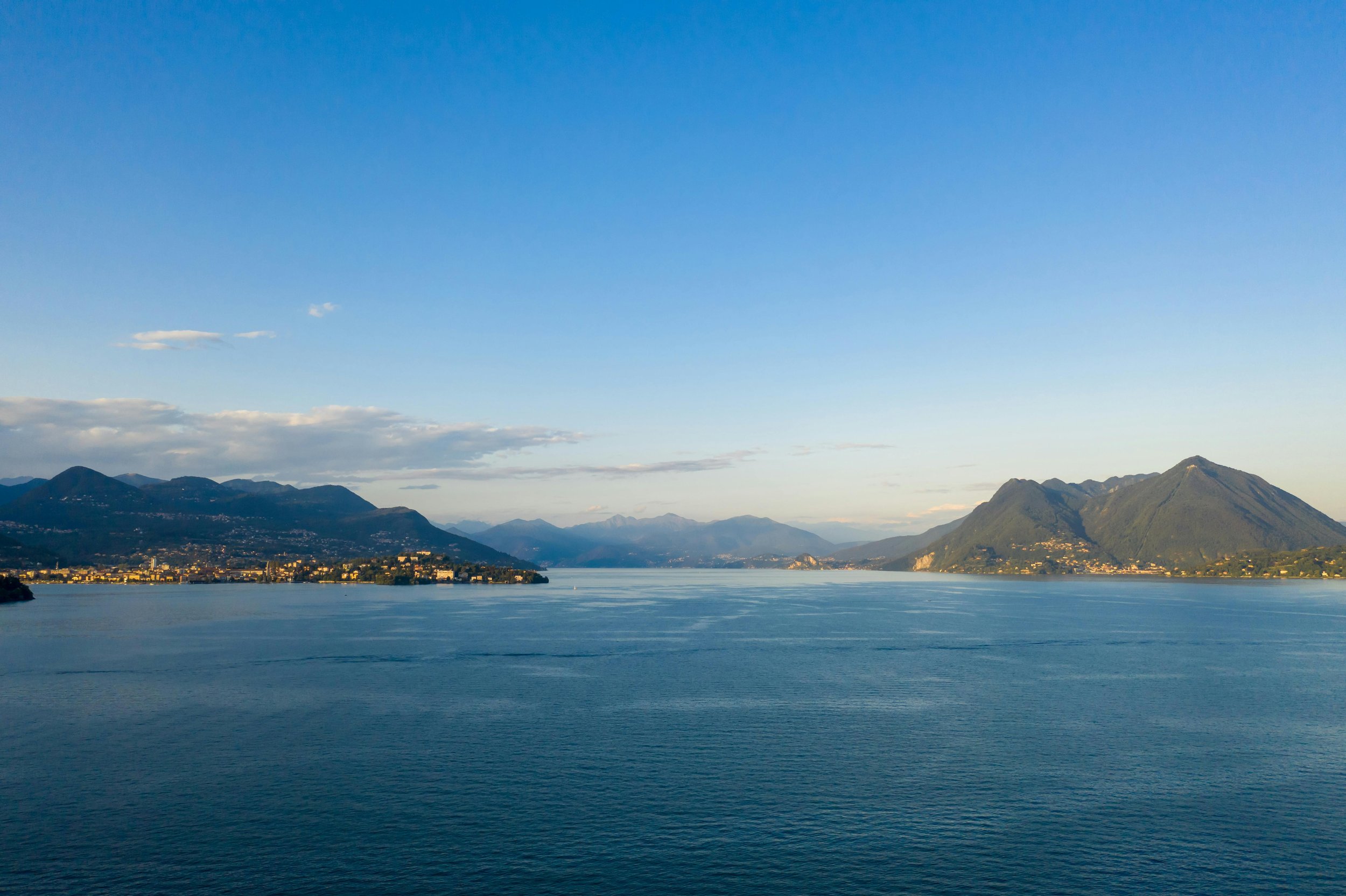 A large lake surrounded by mountains under a clear blue sky with some clouds.