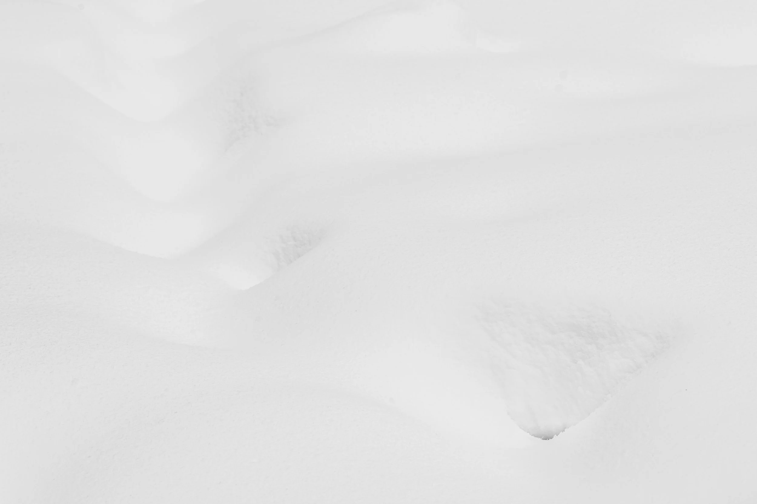 Vue abstraite de dunes de neige immaculées créant des ombres douces et des formes organiques ondulée. Minimalisme