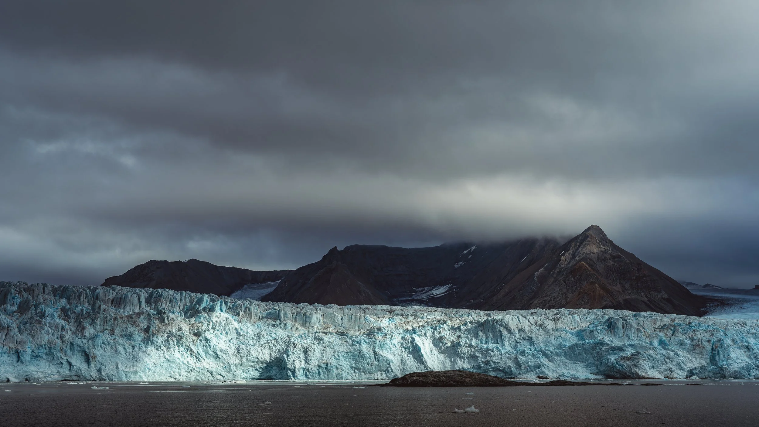 Mur de glace imposant se jetant dans l'océan sous un ciel tourmenté, photographie de nature sauvage et monumentale. Spitsberg
