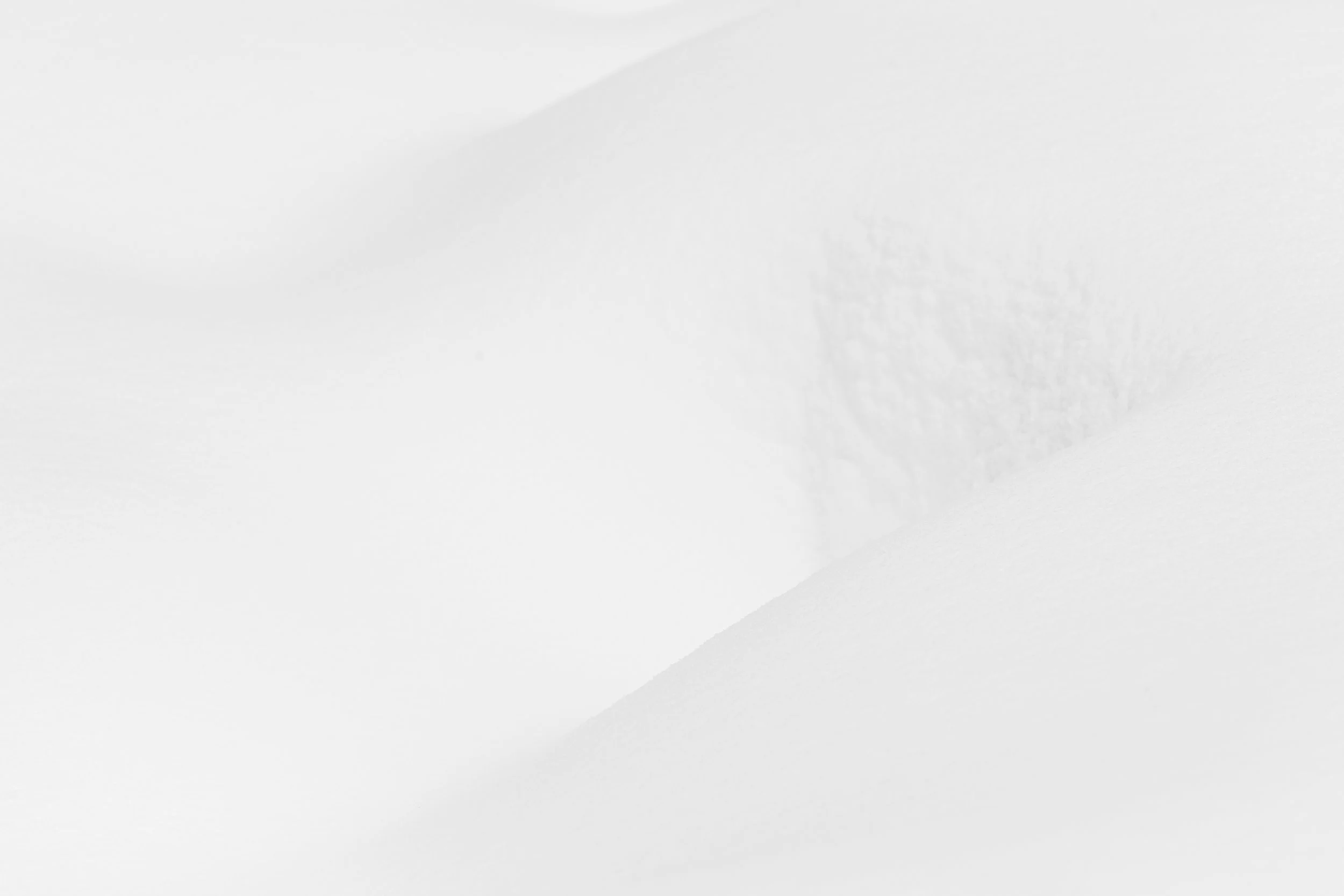 Texture subtile de cristaux de neige sur le flanc d'une congère, jouant avec une lumière très claire. Illusion de partie de corps humain féminin. Minimalisme